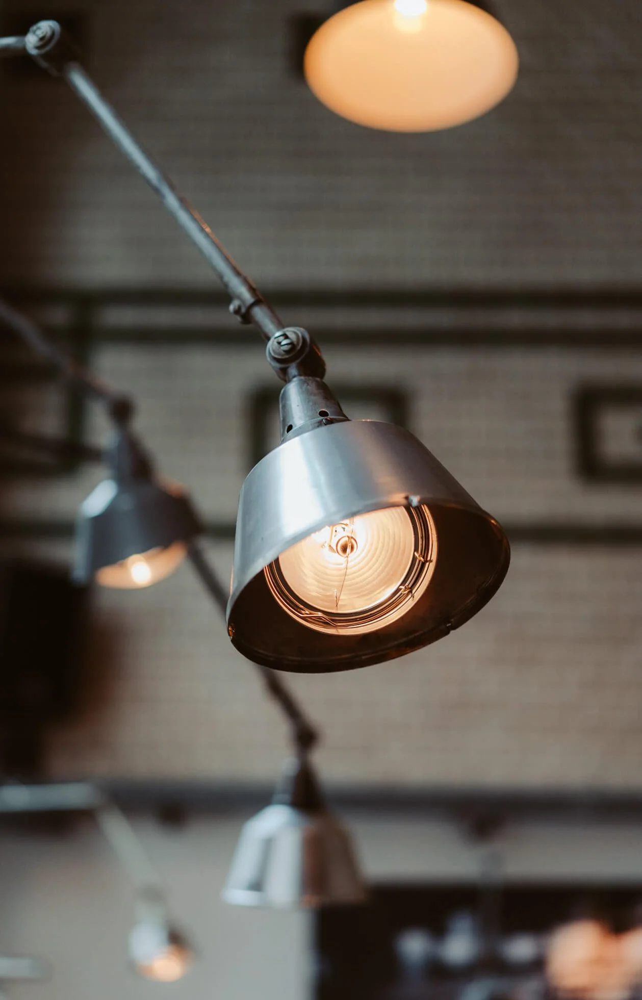 Industrial-style hanging metal light fixture with exposed bulb in a modern interior.