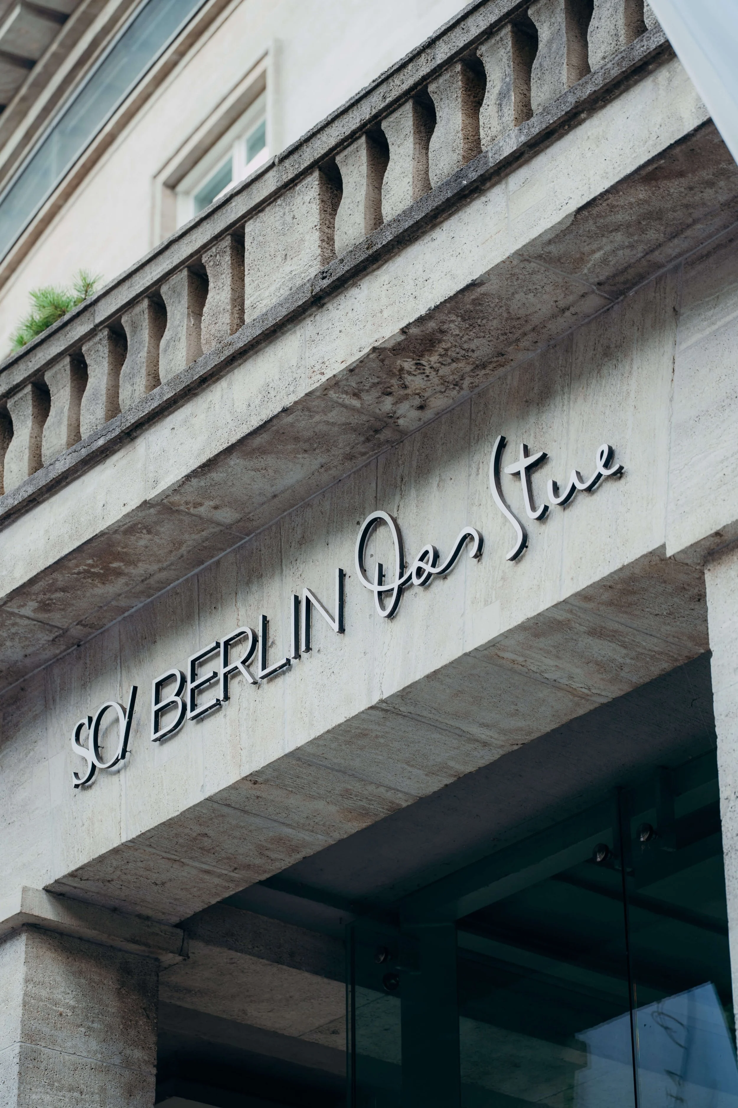 Sign on building reading 'SO/ Berlin Das Stue' in black cursive and capital letters.