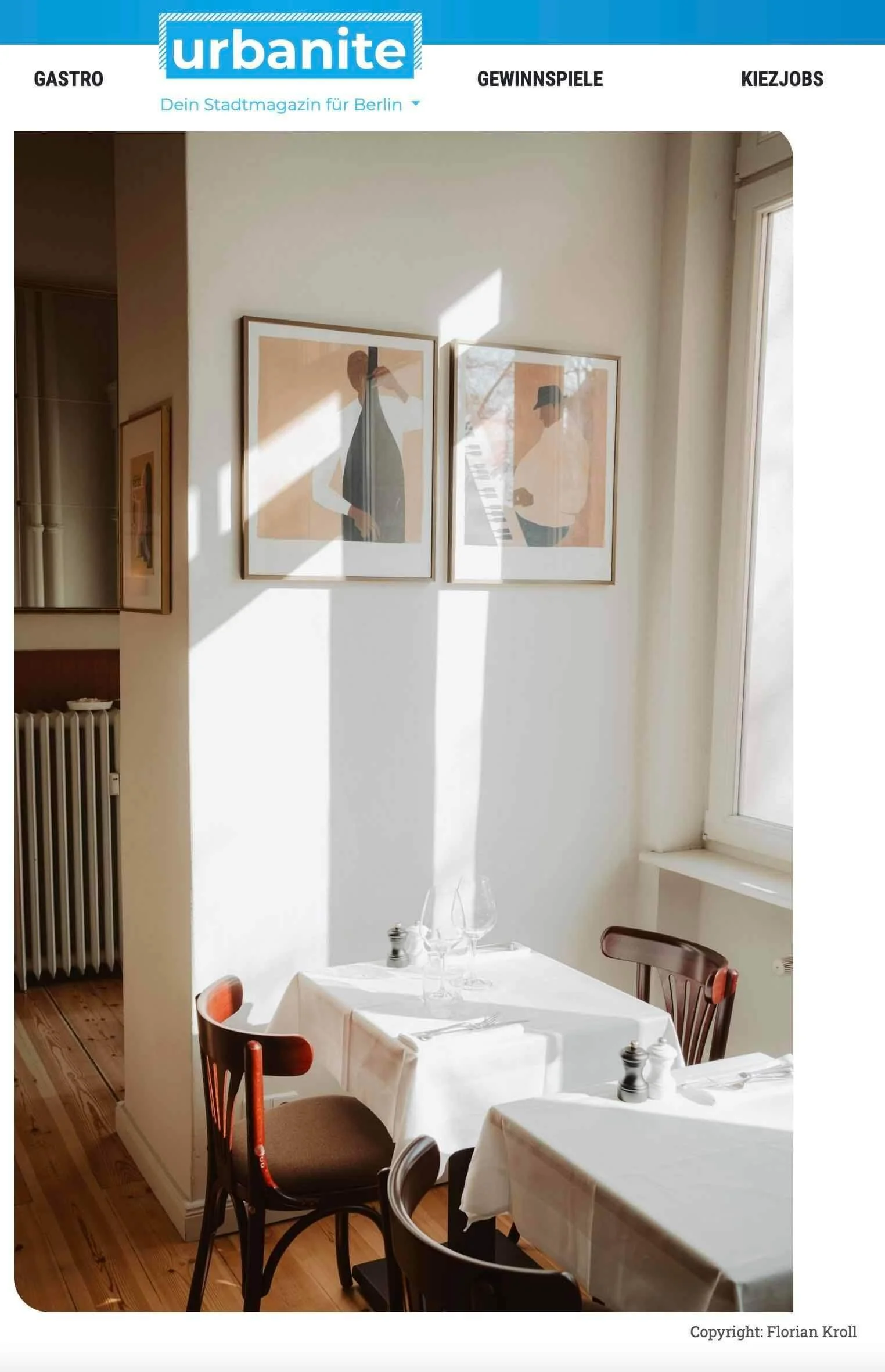 Ein hell erleuchteter Restaurantraum mit weißen Tischdecken, Weingläser, Salz- und Pfefferstreuer, und Stühlen. An der Wand hängen zwei minimalistische, stilisierte Kunstprints von Personen. Sonnenlicht fällt durch ein Fenster und wirft Schatten auf die Wand.