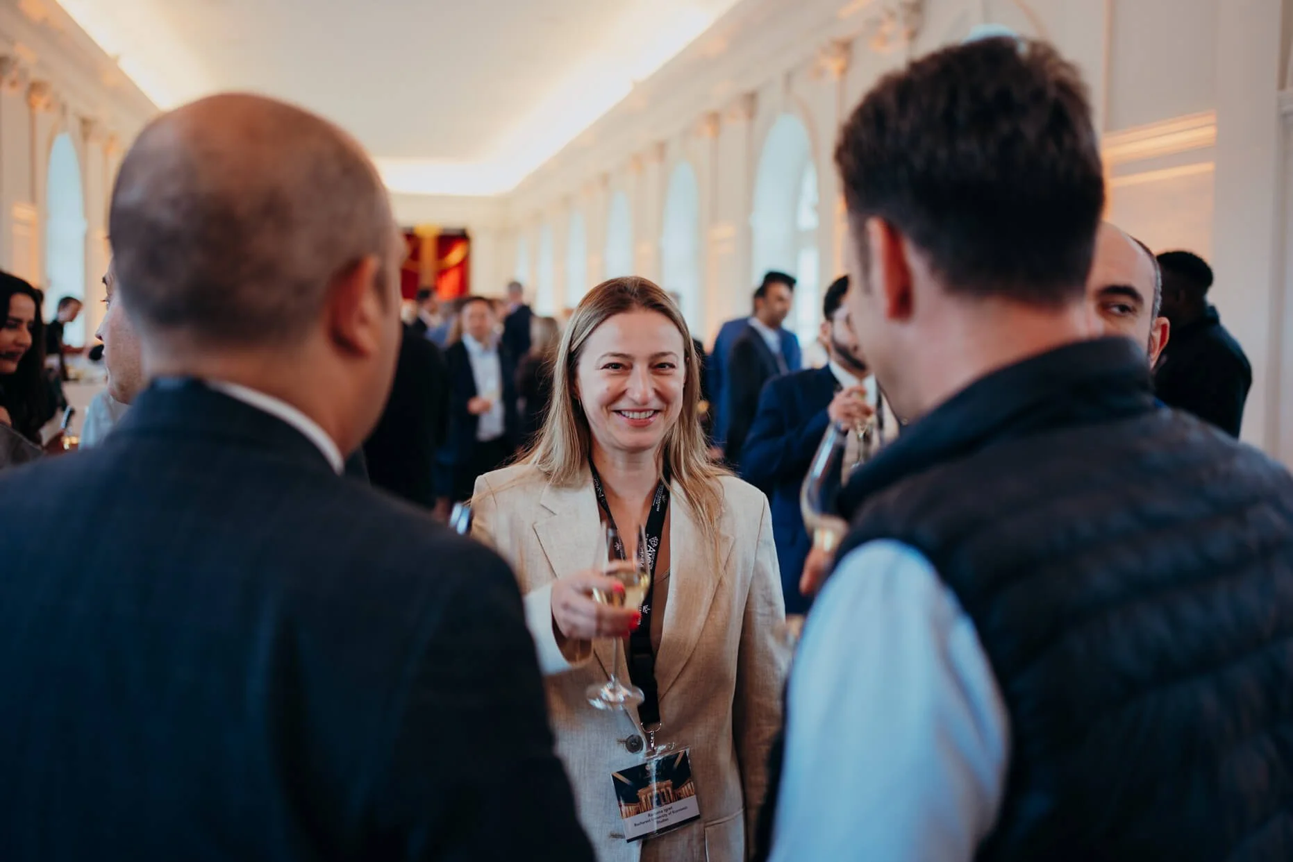 Group of people socializing at a professional networking event in a well-lit, elegant venue.