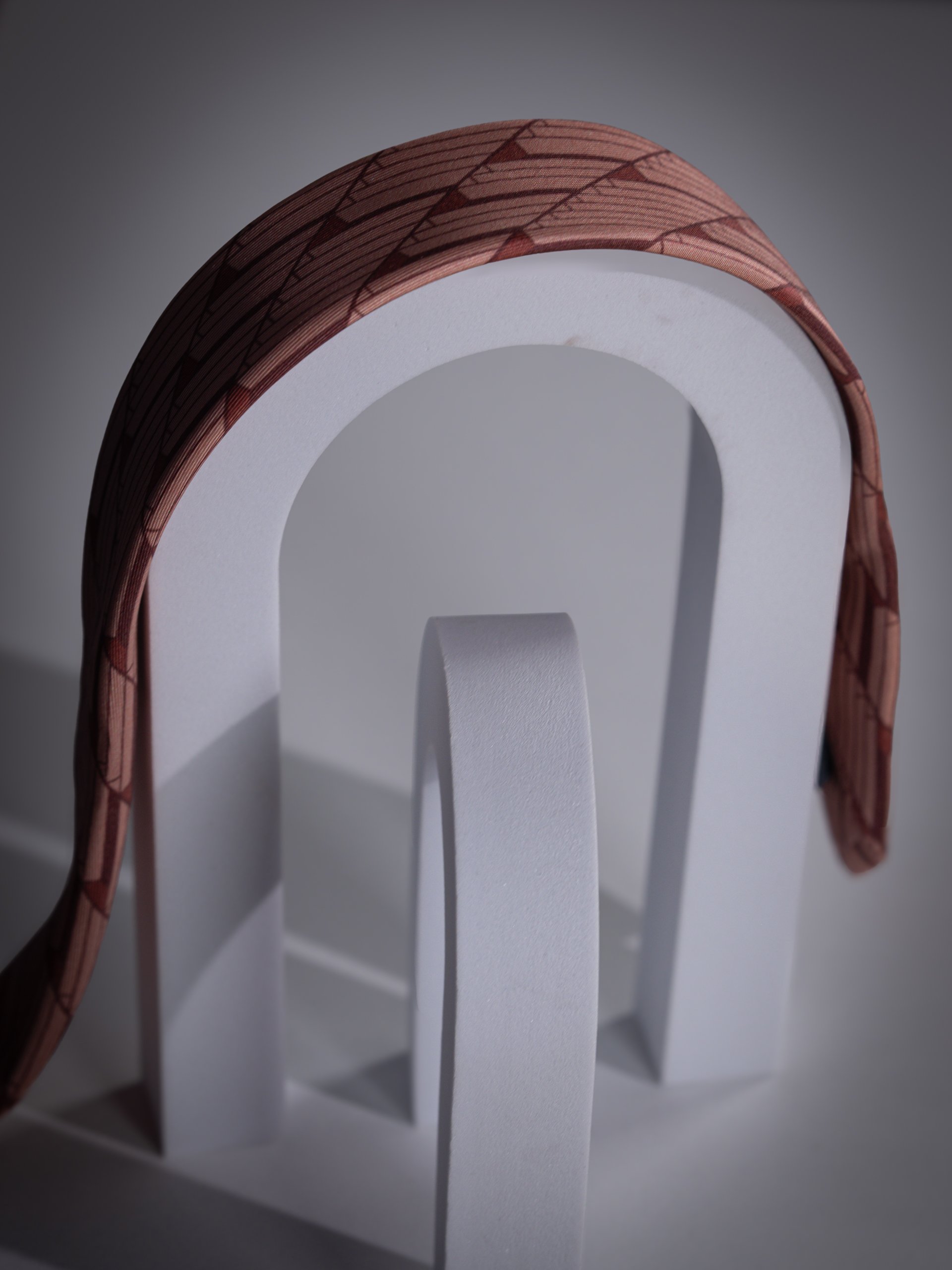 Un oggetto bianco con una forma circolare e un'apertura al centro, circondato da una struttura rossa con un motivo geometrico. Il sfondo è di colore grigio scuro.