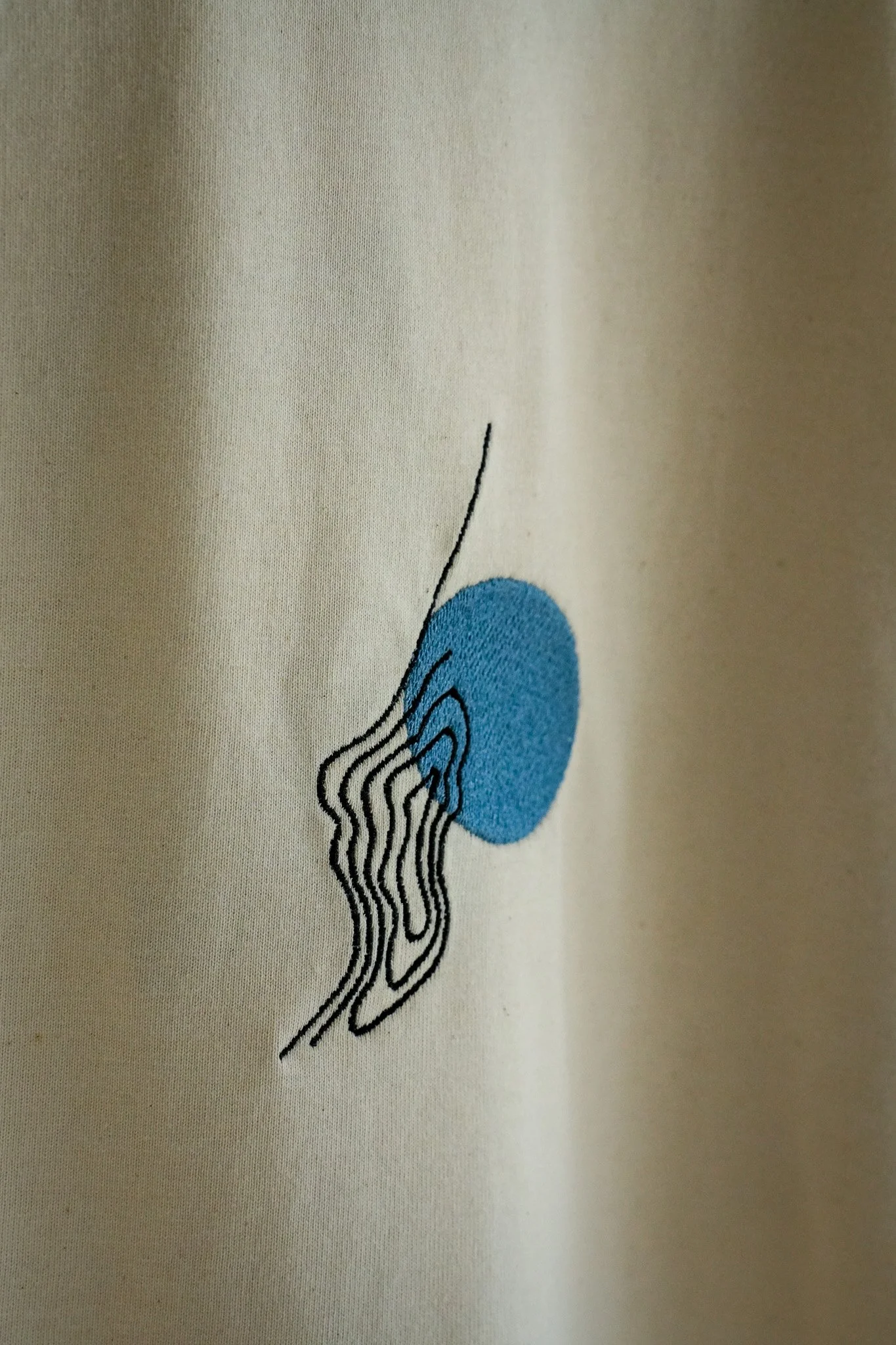 Close-up of a fabric with a small embroidered abstract design in black and blue.