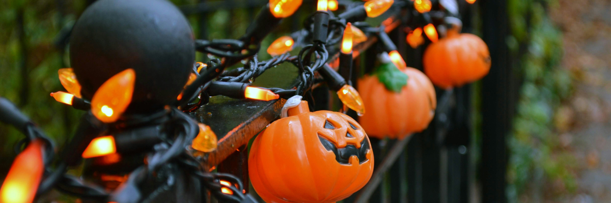 Pumpkin shaped fairy lights entwined on an outdoor railing.