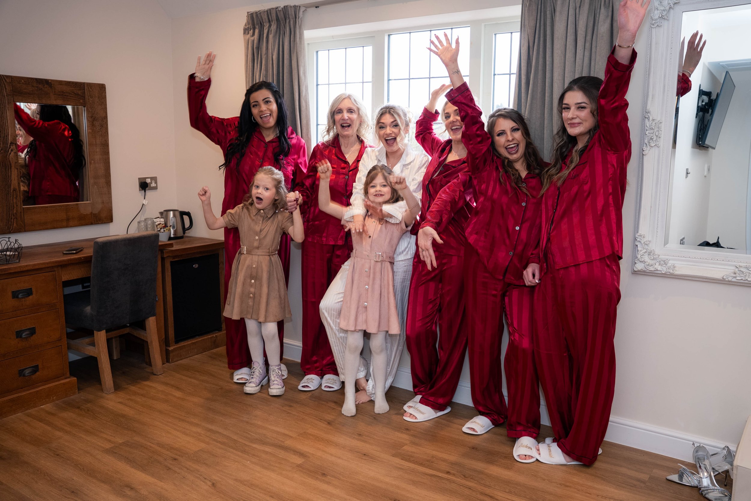 Group of women and children celebrating in pajamas, with many raising their arms and smiling.