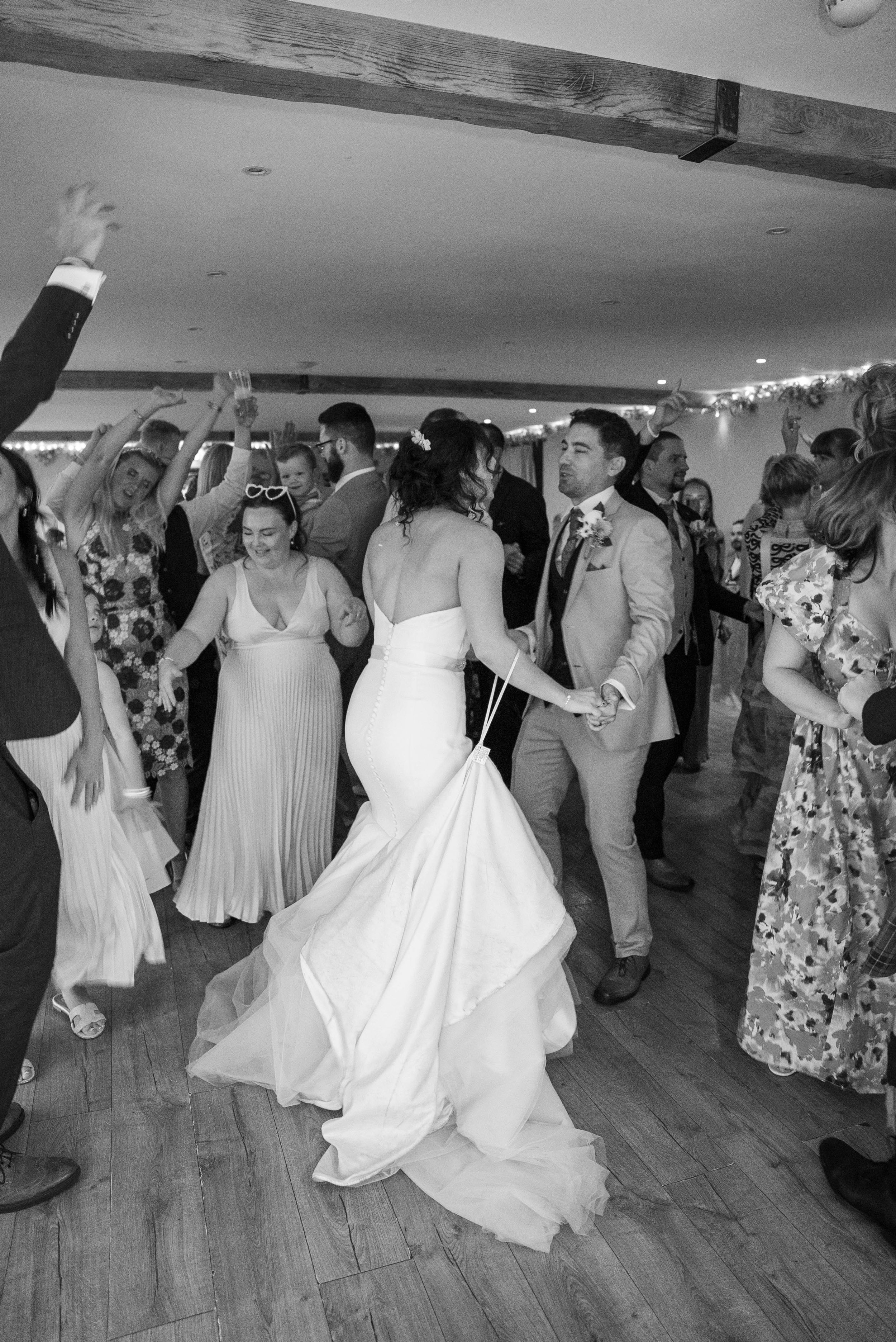 A bride and groom dancing at their wedding reception surrounded by guests celebrating and dancing.