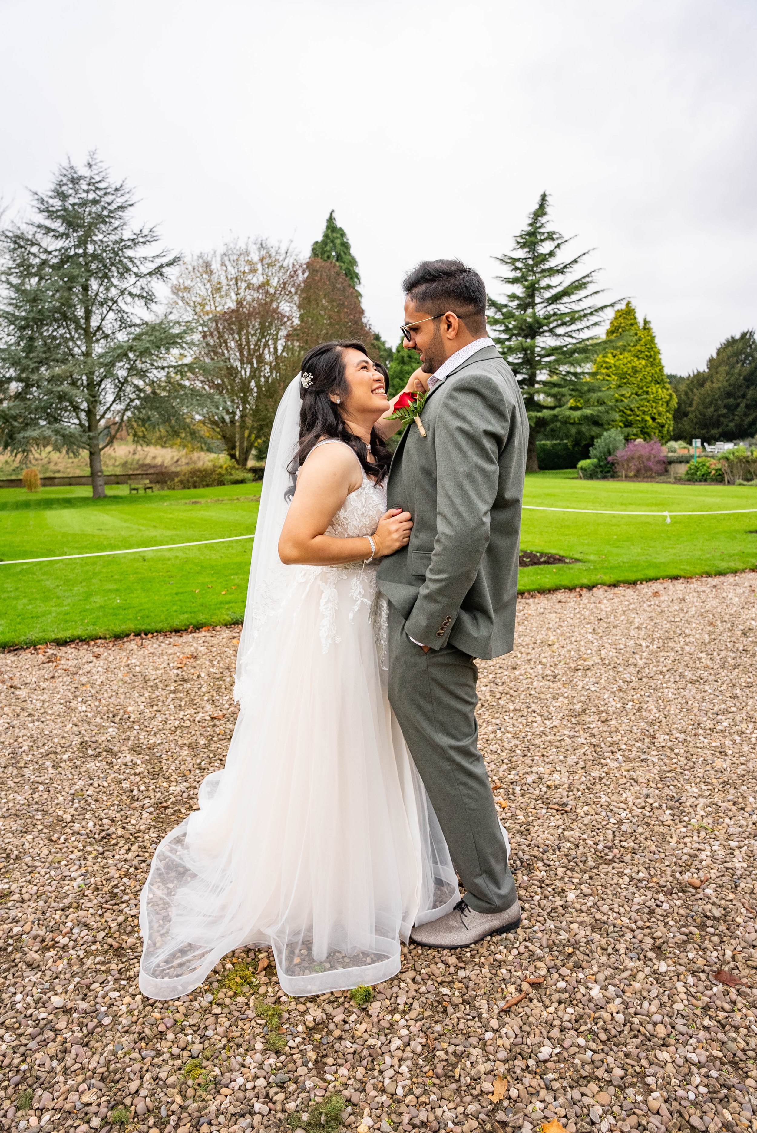 A bride and groom smiling at each other outdoors on their wedding day.
