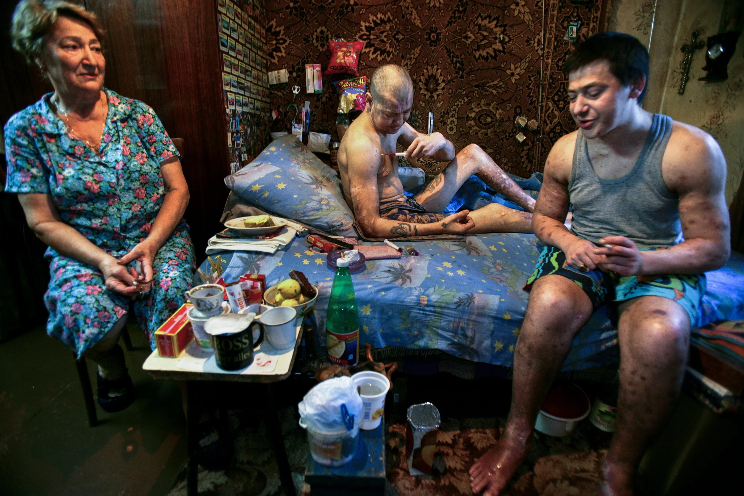 POLTAVA, UKRAINE - AUGUST 12 2005: In a small apartment in a poor neighbourhood of Poltava, two brothers shoot up drugs while their mother looks on helpless in her own home. Alla, left, is the mother of Dima, 39, middle, and Ruslan, 36, right. They h