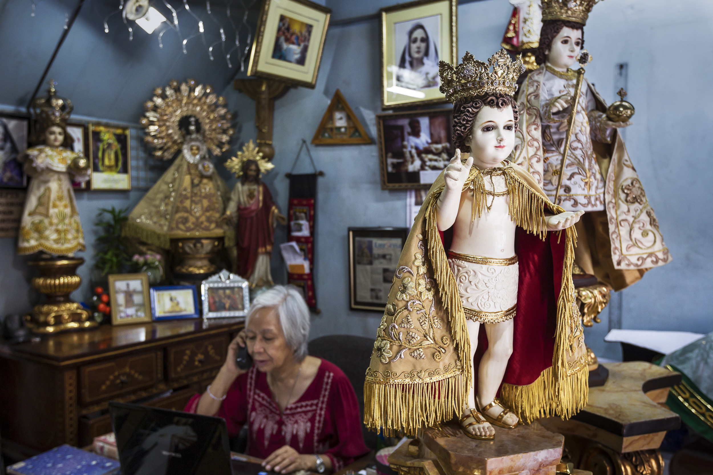MANILA, PHILIPPINES, JANUARY 2012: Catholic icon dealer Nene Bernales and embroidery staff at work in her shop in Manila, Philippines, 25 January 2012. They are surrounded by Icons that have heads and hands made of Ivory. Nene's husband Marcial Bern