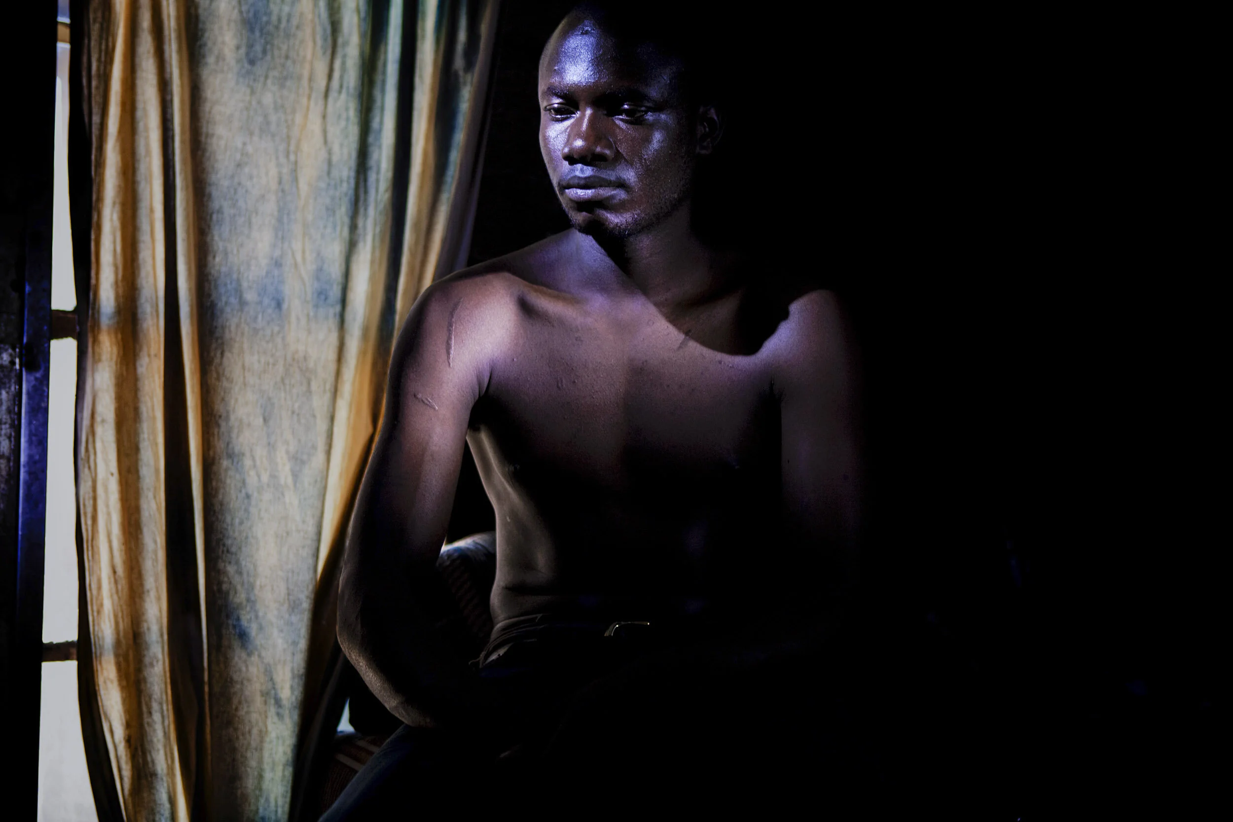 HARARE, ZIMBABWE, JUNE 2009: A young MDC activist, 25, name withheld, sits quietly in a bedroom he rents in a shack in a makeshift township in Harare, Zimbabwe, 22 June 2009. The young man is the district security officer for the MDC in Harare East