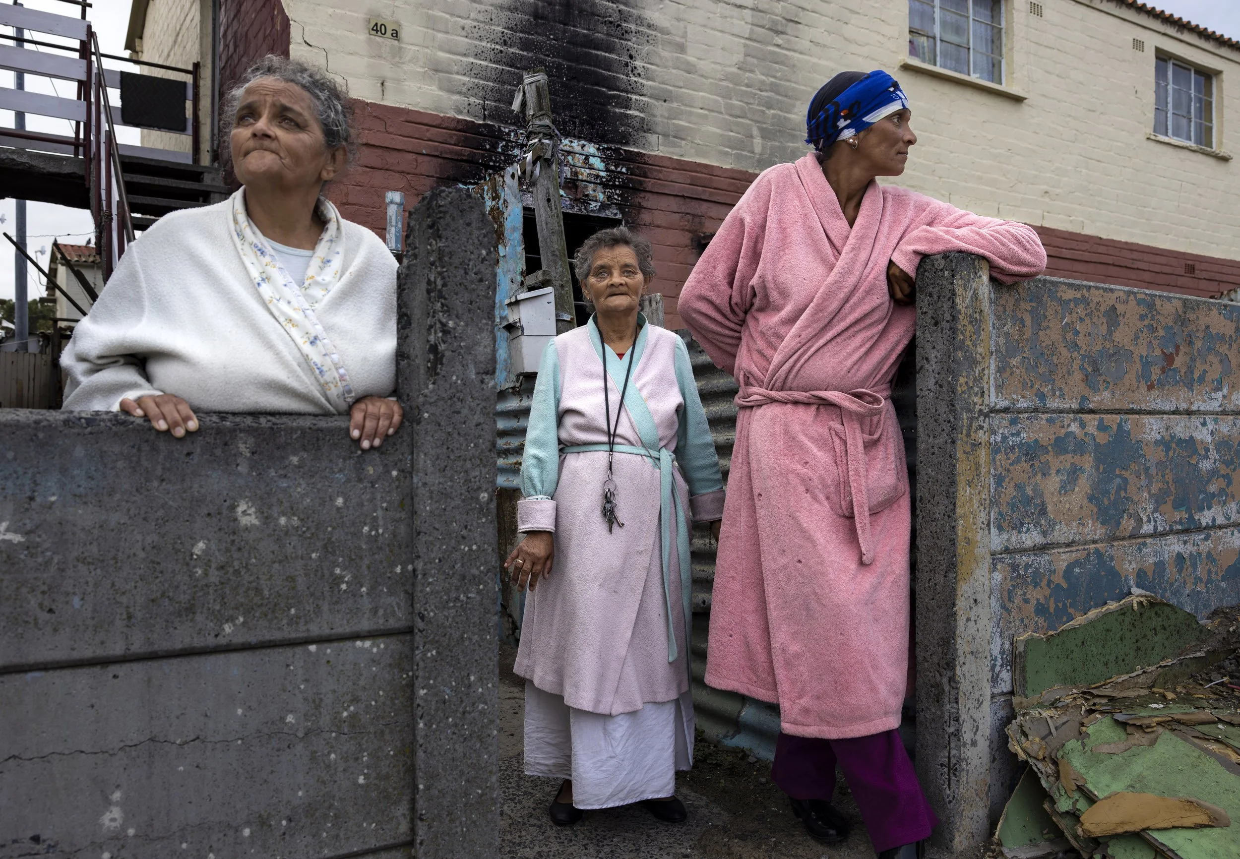HANOVER PARK, CAPE TOWN, SOUTH AFRICA: Three ladies who live above a burned out former “Tik” house come down to the street in their dressing gowns early in the morning. Tik is the local Afrikaans word for meth amphetamine, which is a cheap and popul
