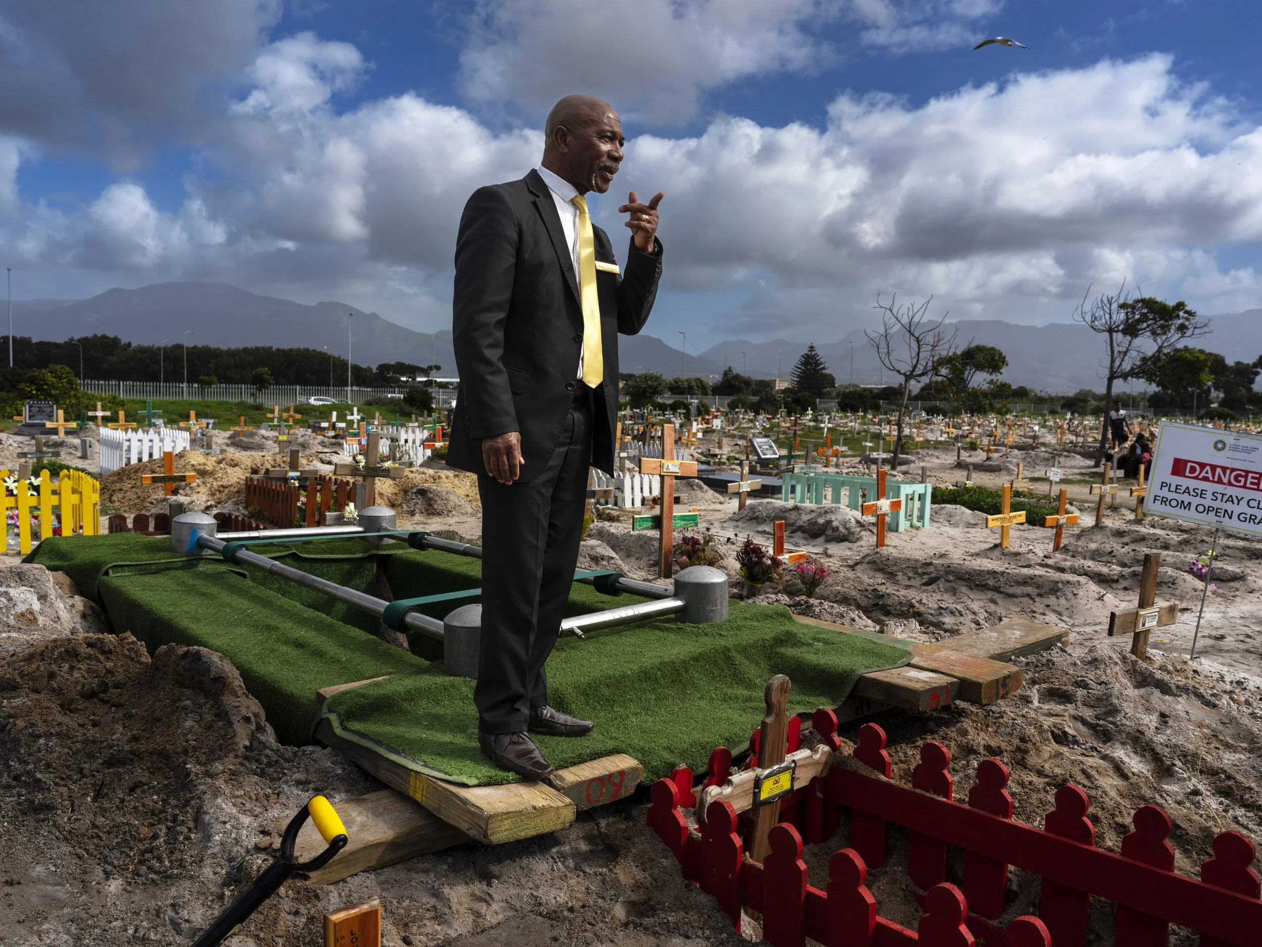 GRASSY PARK, CAPE FLATS, SOUTH AFRICA: An undertaker waits for a funeral party at a gravesite in Grassy Park cemetery. Cape Town has one of the highest murder rates in the world, with an average of ten per day. Many of those murders are gang and cri