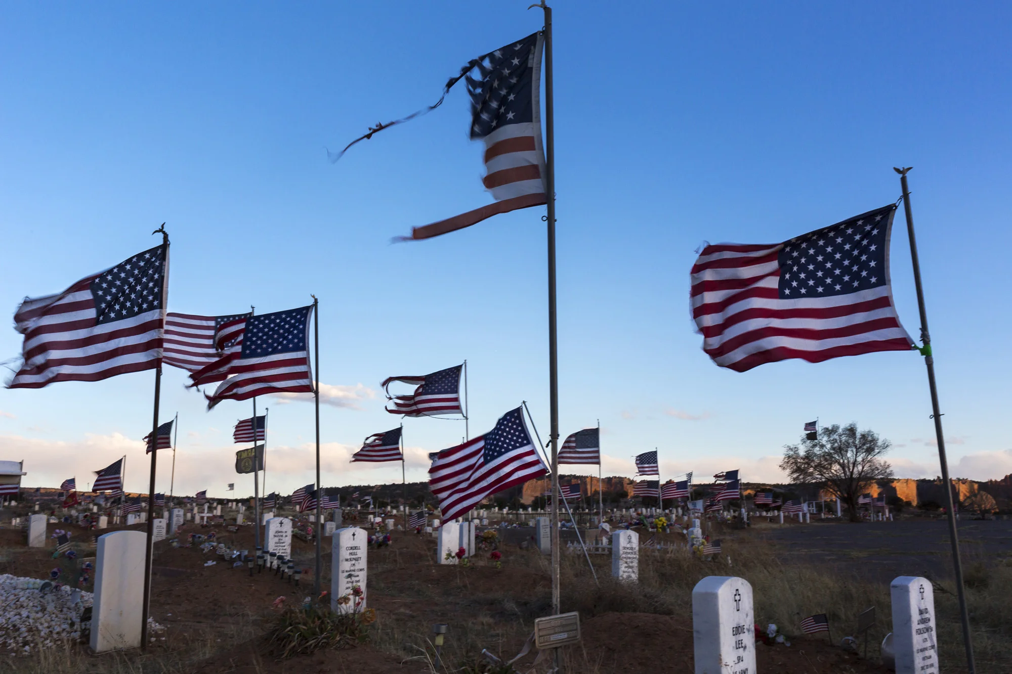 WINDOWROCK, ARIZONA, 4 APRIL 2014: Flags flutter in the last light at a Navajo US Military veterans cemetry in the Navajo capital WindowRock, Arizona. The Navajo have a long and distinguished history of serving with valor in the US armed forces. (Ph