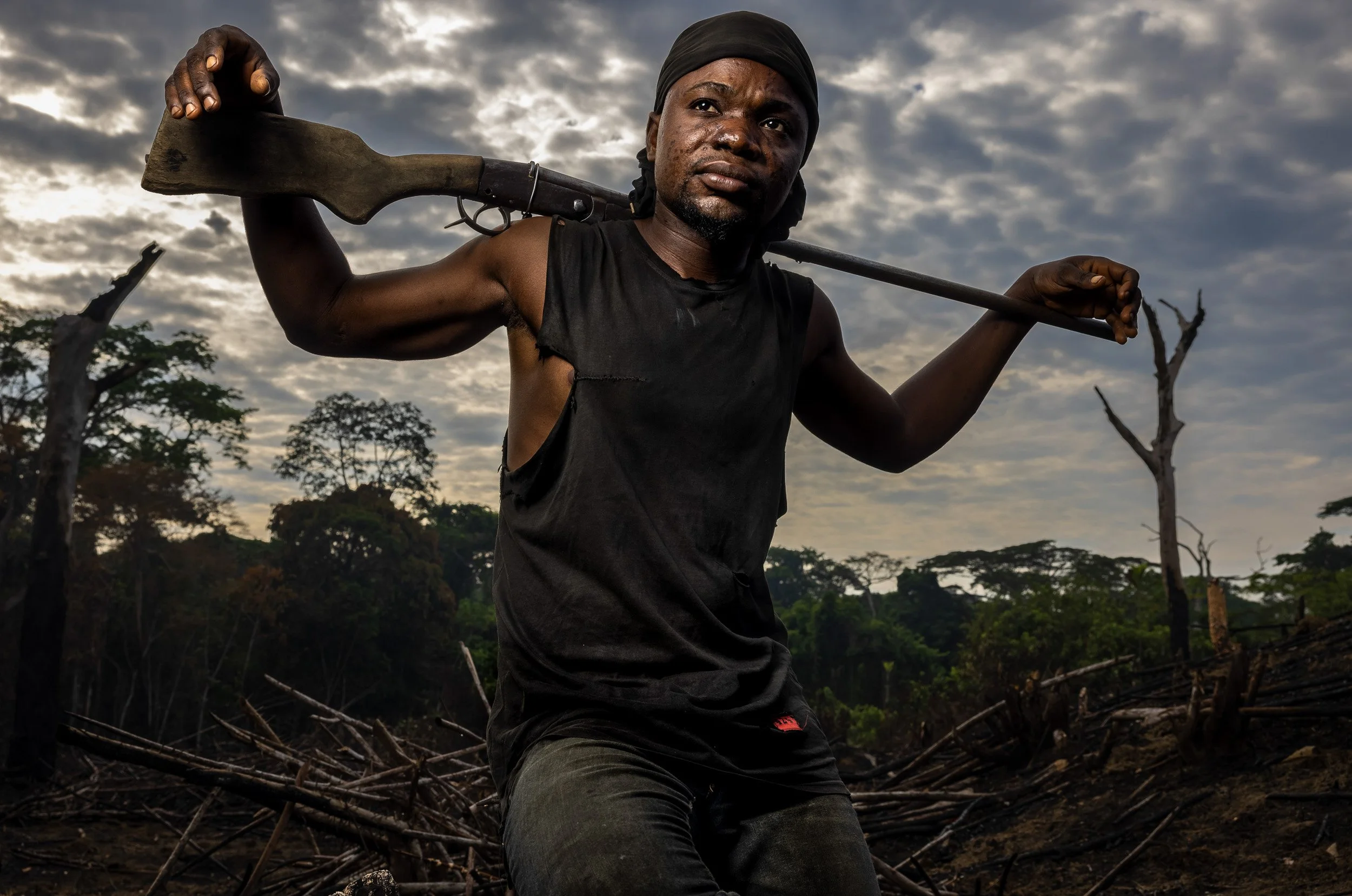 LEFONDO VILLAGE, BOENDE DISTRICT, TSHUPA PROVINCE, DEMOCRATIC REPUBLIC OF CONGO, 25 APRIL, 2021: Bushmeat hunter Arthur Bengo, 28, sits for a portrait in the early morning outside his village of Lefondo, about 30kms outside of Boende town. The scars