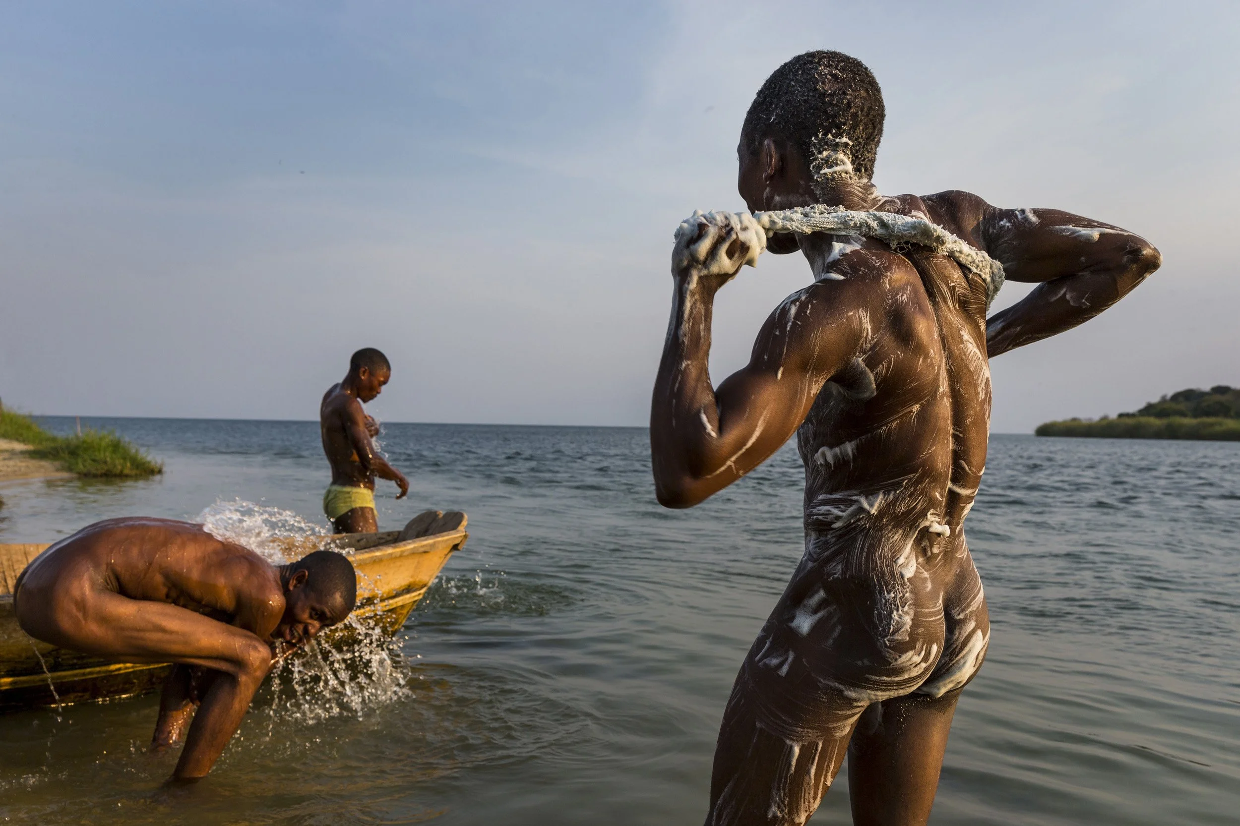 ISHANGO, LAKE EDWARD, DEMOCRATIC REPUBLIC OF CONGO. 11 AUGUST 2013: Local men bathe in the Semliki River as it flows into Lake Edward, Ishango, DRC, 11 August 2013. This river and the Lake itself are inside Virunga National Park, a World Heritage si