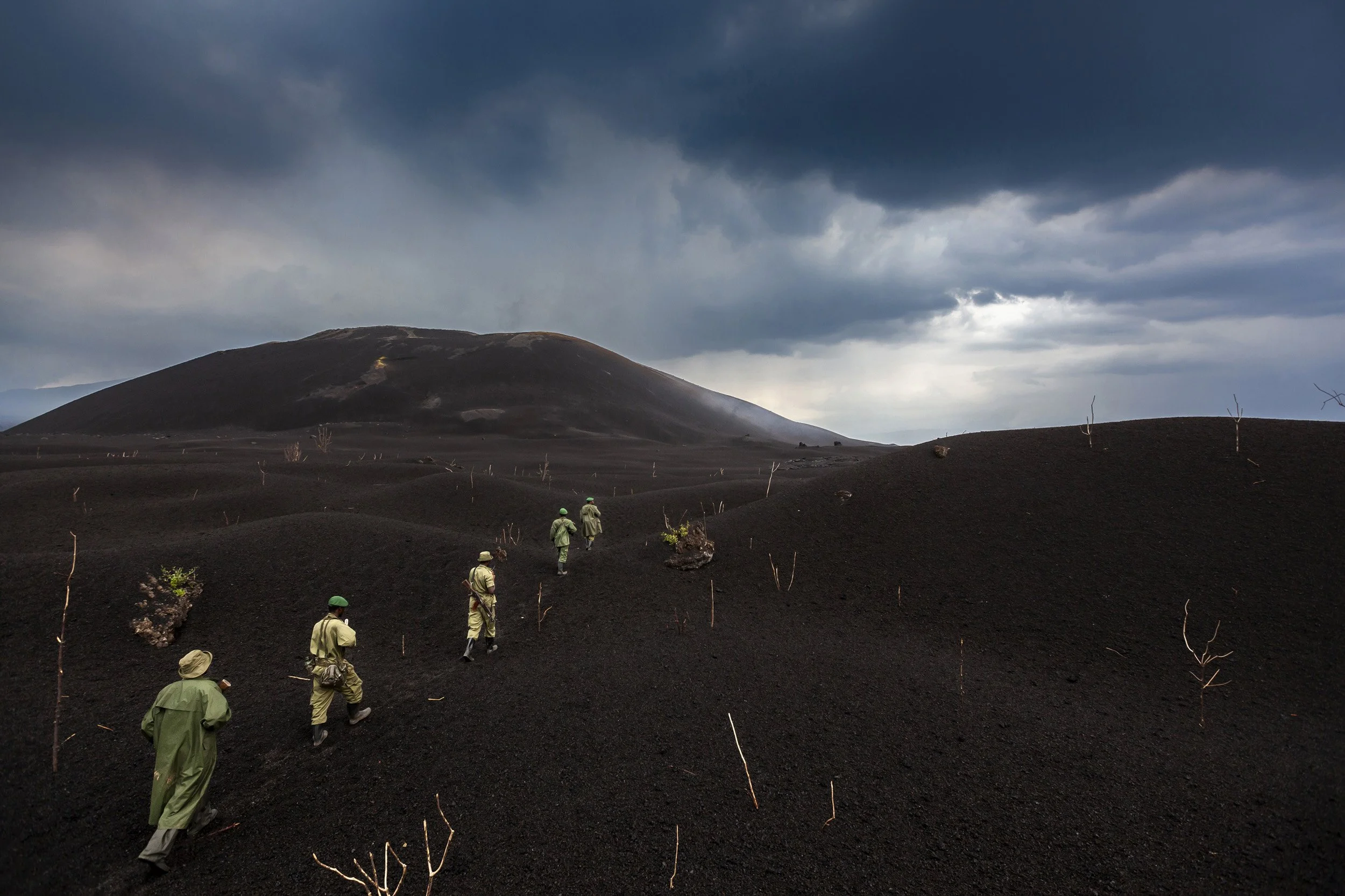 Conservation rangers walk carefully through the ashfield of a newly formed volcano inside Virunga National Park.