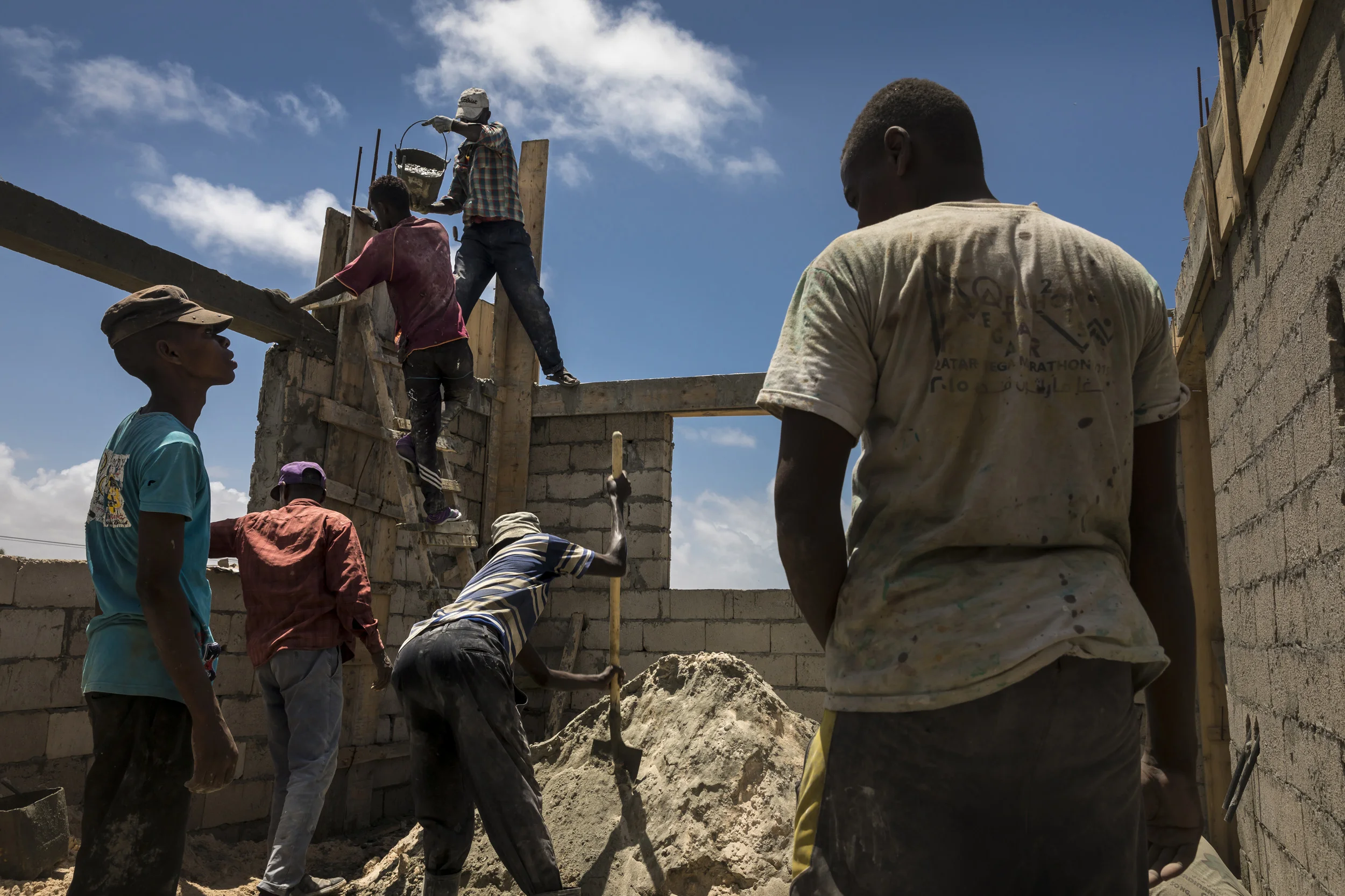 MOGADISHU, SOMALIA, 2 AUGUST 2017: Local builders work on a new house on the foreshore of Mogadishu. Surrounded by buildings ruined by the civil war, new money from the Somali diaspora is now investing in this area, a former beach paradise before th