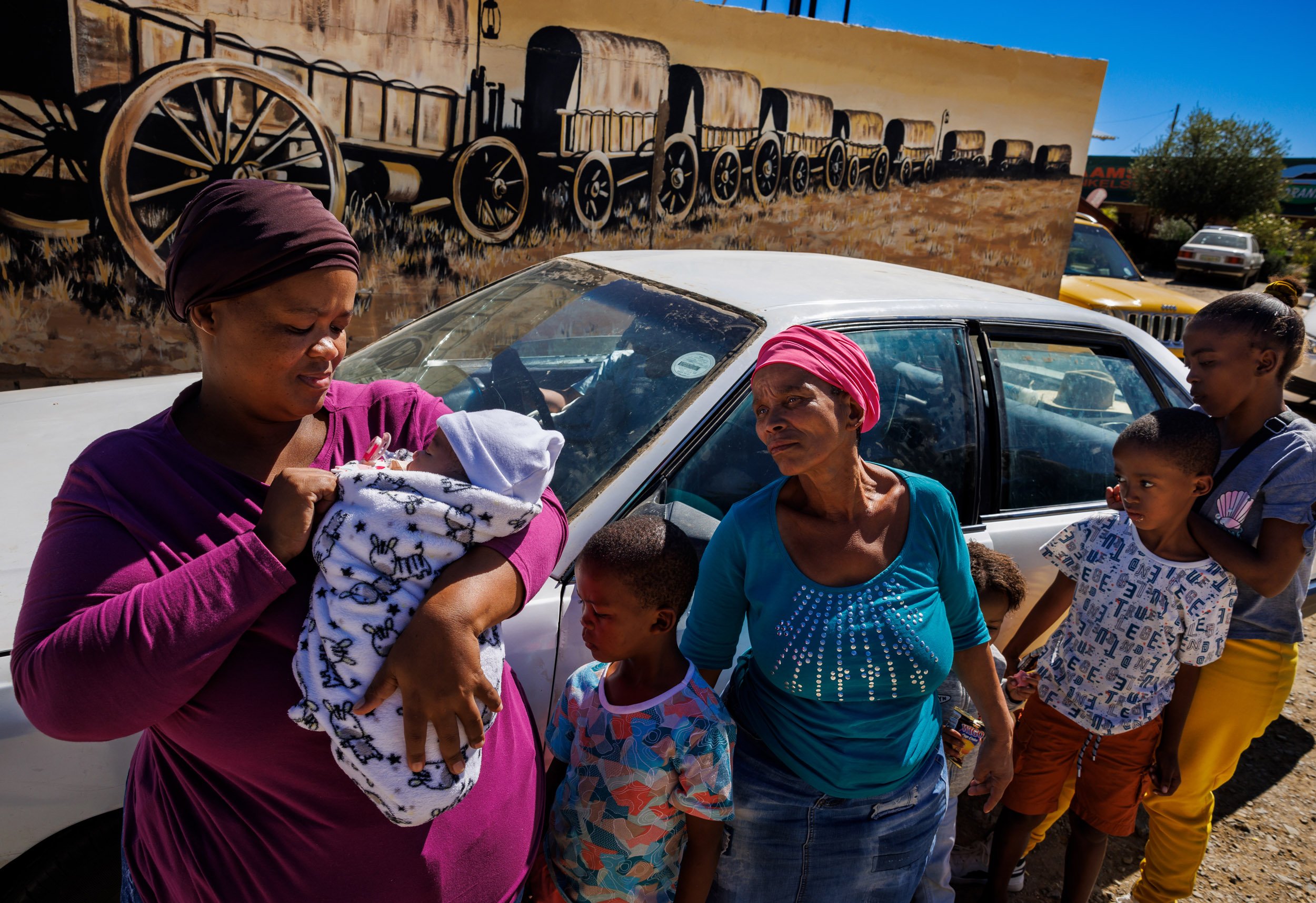 ORANIA, NORTHERN CAPE, SOUTH AFRICA, 15th April 2023: Farm labor workers from neighboring farms stop at Orania's supermarket to buy groceries on a regular basis. The mural behind them depicts the great trek of the 1800's, when most of the Afrikaner