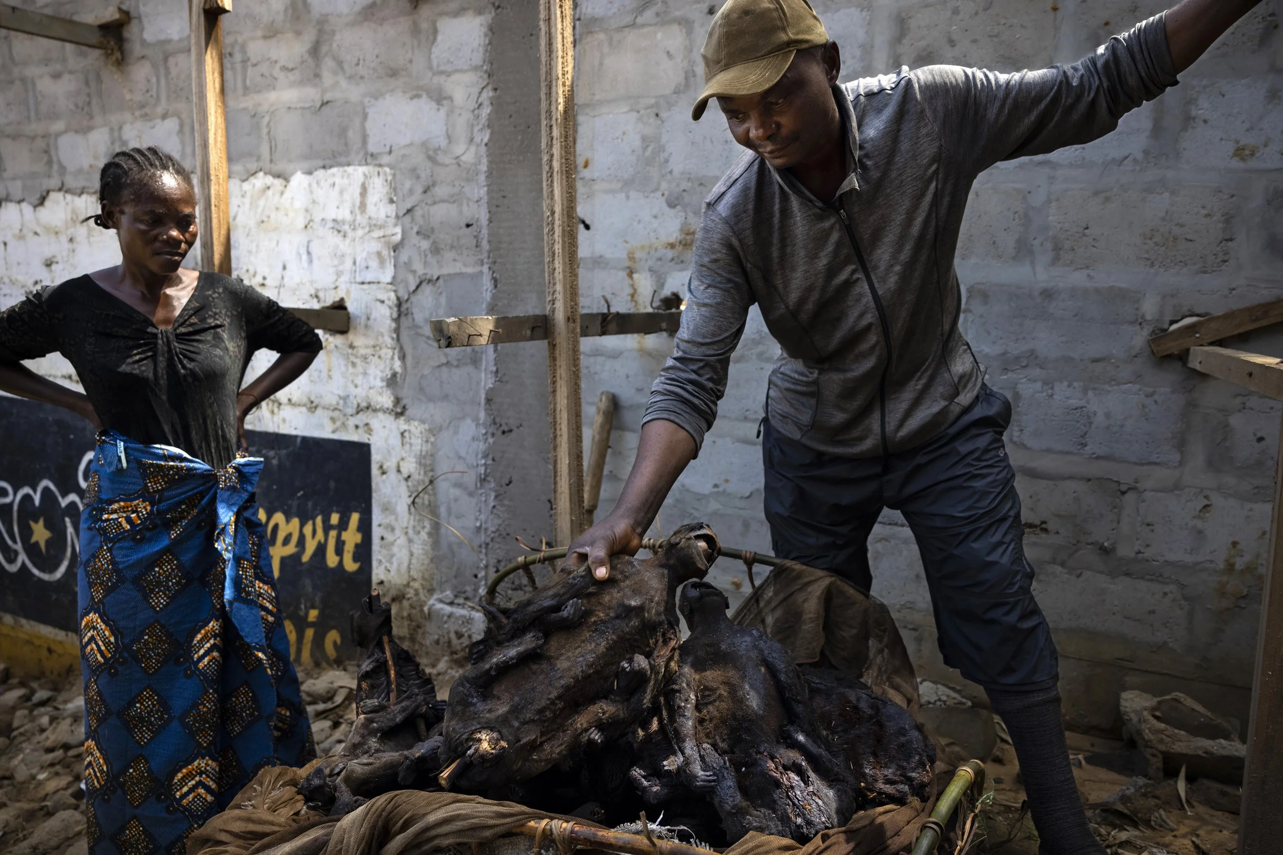 KINSHASA, DEMOCRATIC REPUBLIC OF CONGO: A man and his wife unpack a bushmeat package of 54 monkeys that they have just unloaded from a boat in Maluku port. There are two different species. The couple say they have a shotgun with relatives in the Equ