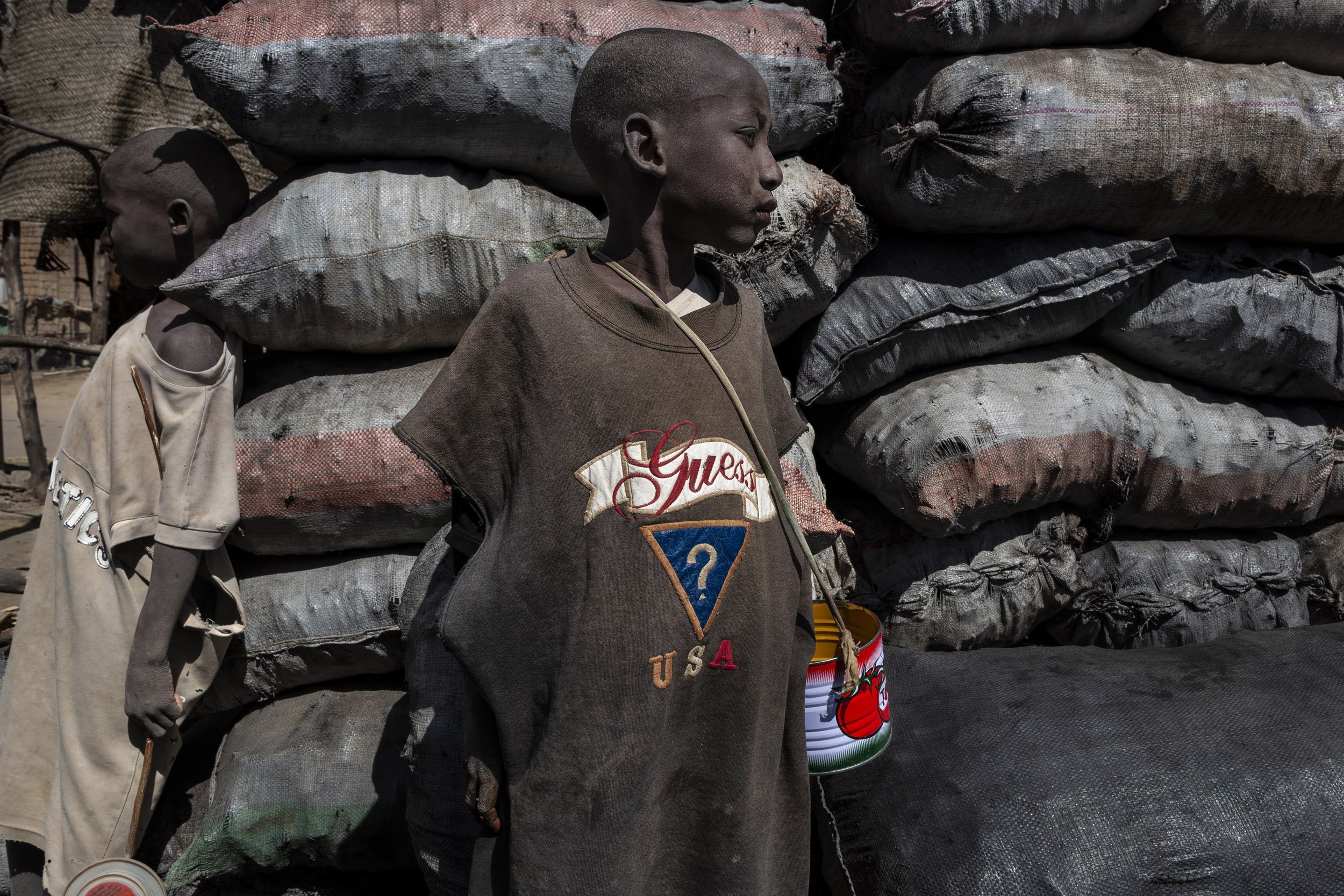TIMBUKTU, MALI, JANUARY 2010: Young boys with begging tins in a coal yard in Timbuktu, January 19, 2010. These young boys are sent by their parents from poor communities to the local Marabou who functions as a surrogate parent while ensuring some k