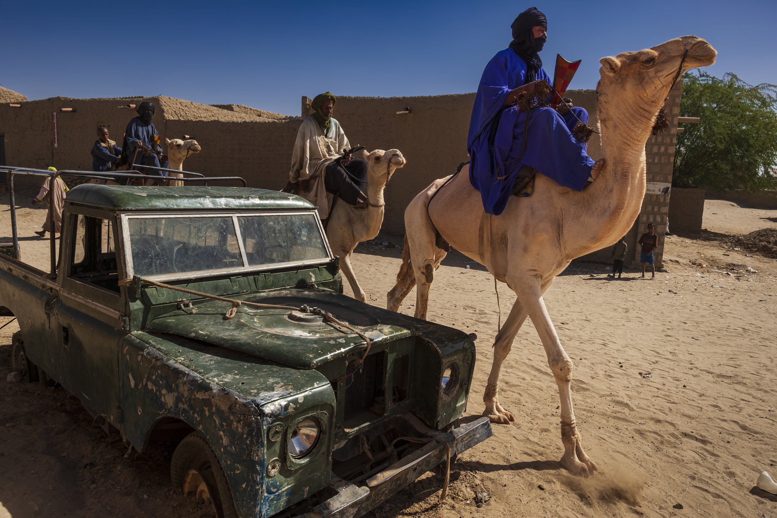 TIMBUKTU, MALI, JANUARY 2010: Tuareg men from an outlyingTuareg community arrive in town and walk their camels through the streets of Timbuktu, the mythical Northern Mali city, on their way to visit with relatives in the city. January 23, 2009. (Pho