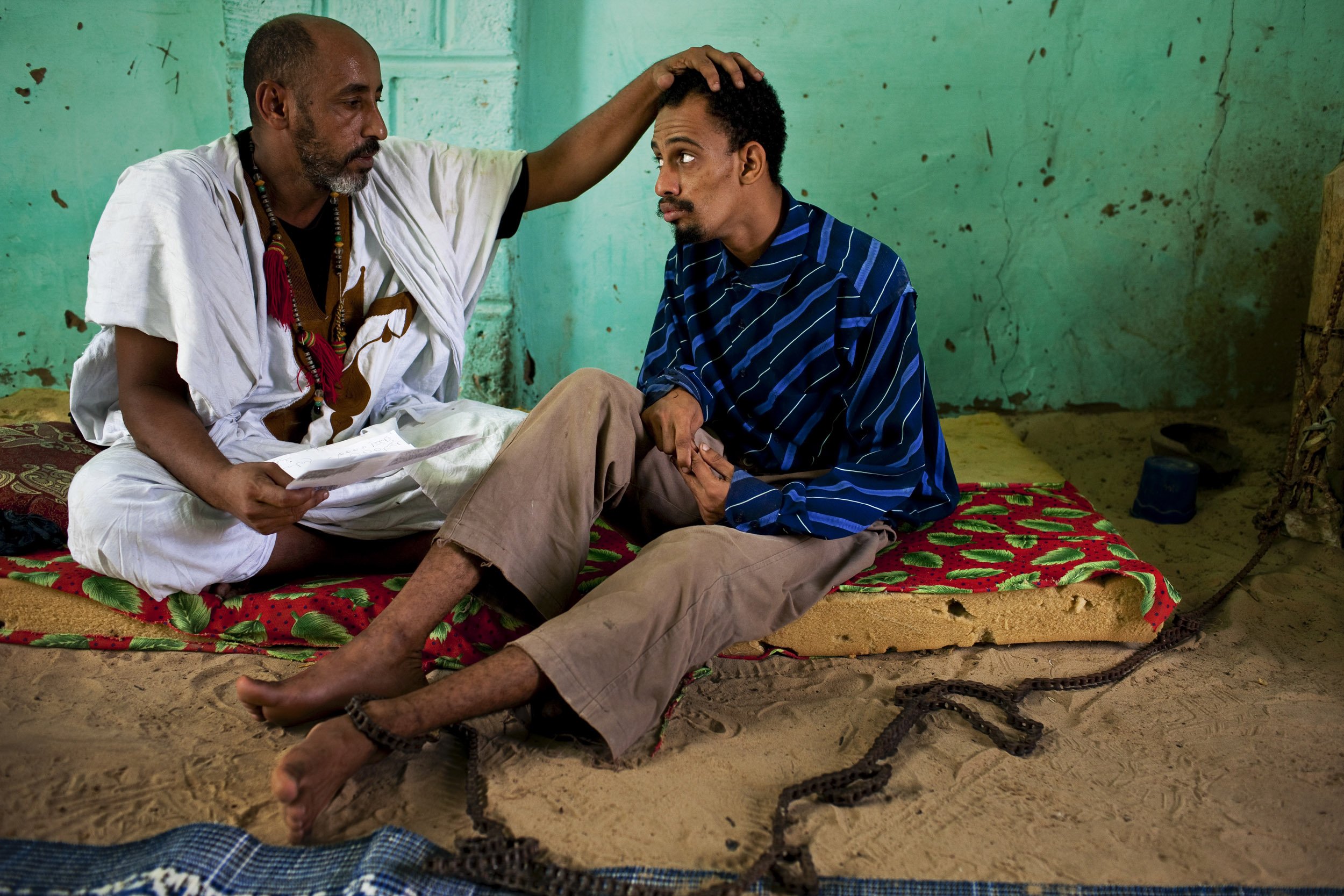 TIMBUKTU, SEPTEMBER 2009: Timbuktu Marabout Mohamed Lamine ould Seing Almoustapha counsels a psychologically disturbed man who is chained to a post in the Marabout's home, 19 September 2009. Marabout's are the Timbuktu equivalent of a therapist but