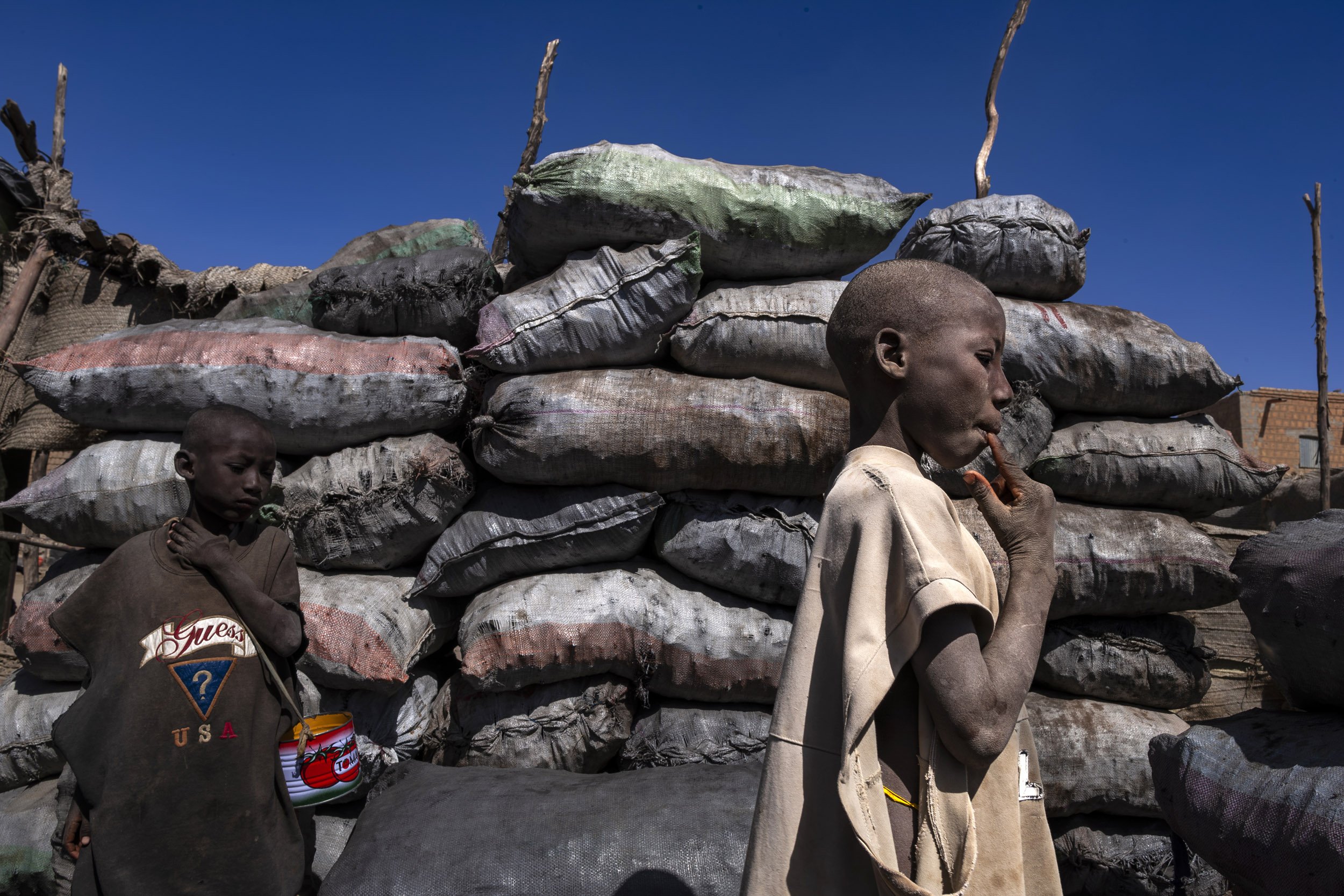 TIMBUKTU, MALI, JANUARY 2010: Young boys with begging tins in a coal yard in Timbuktu, January 19, 2010. These young boys are sent by their parents from poor communities to the local Marabou who functions as a surrogate parent while ensuring some k