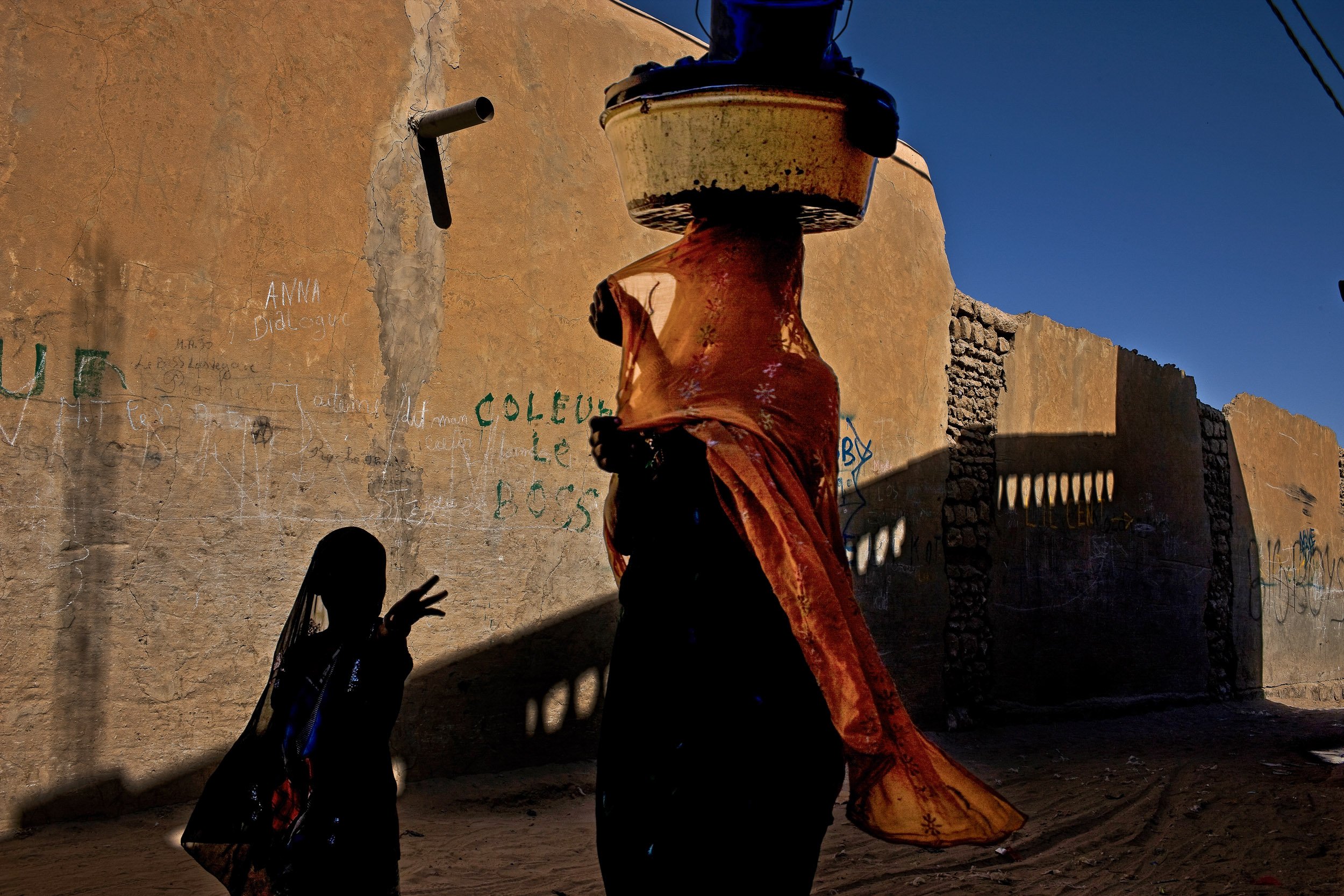 TIMBUKTU, MALI, JANUARY 2010: A women and child walk past the camera in a back alley street scene in Timbuktu, the mythical Northern Mali city, January 20, 2010 (Photo by Brent Stirton/Reportage by Getty images.)