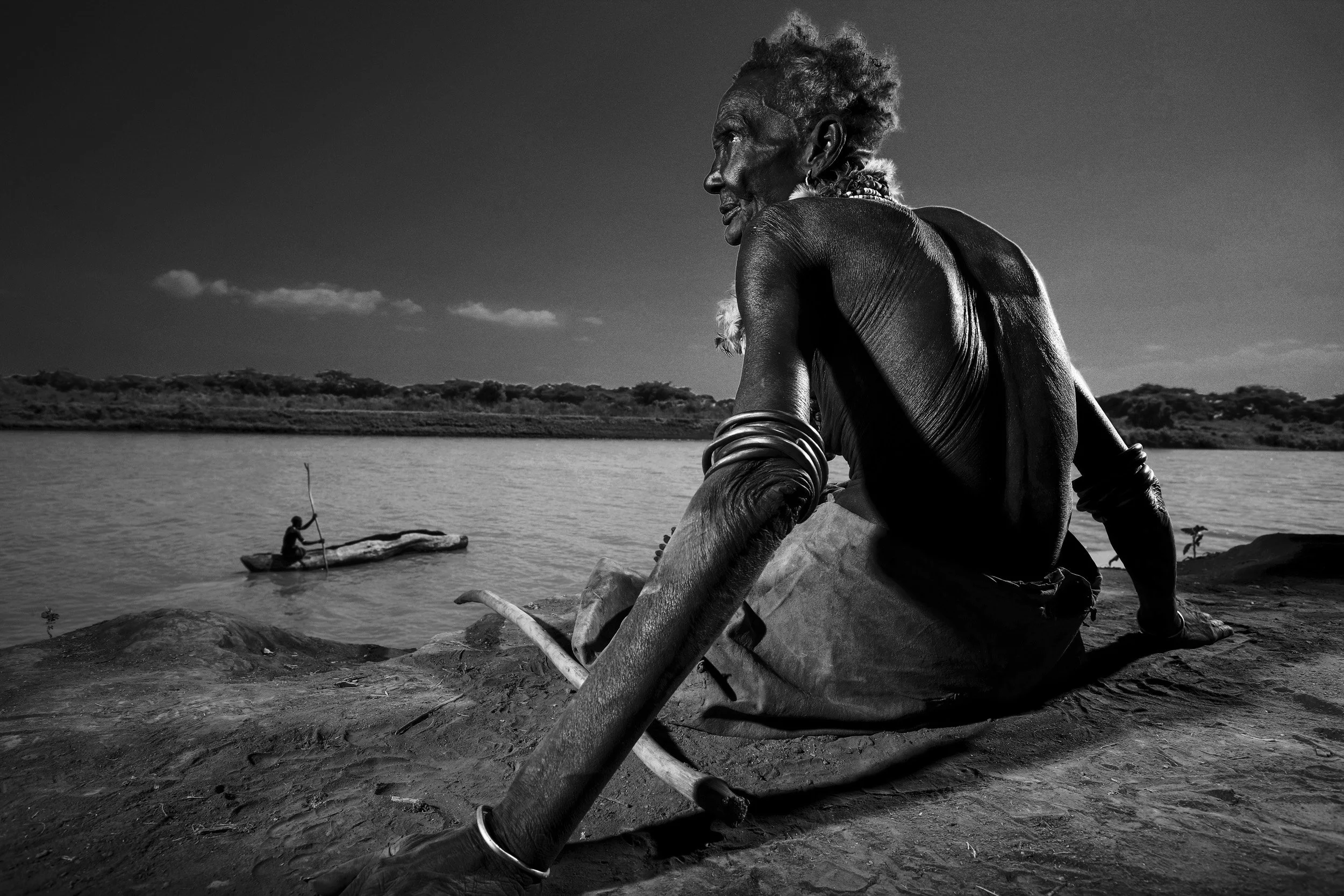 LORYRA, SOUTH OMO, ETHIOPIA, DECEMBER 2007: A elderly Dassanech women sits on the banks of the Omo river in the Lower Omo Valley, South West Ethiopia. Ethiopia has created three large dams and as a result has shrunk the Omo river to one fifth of its