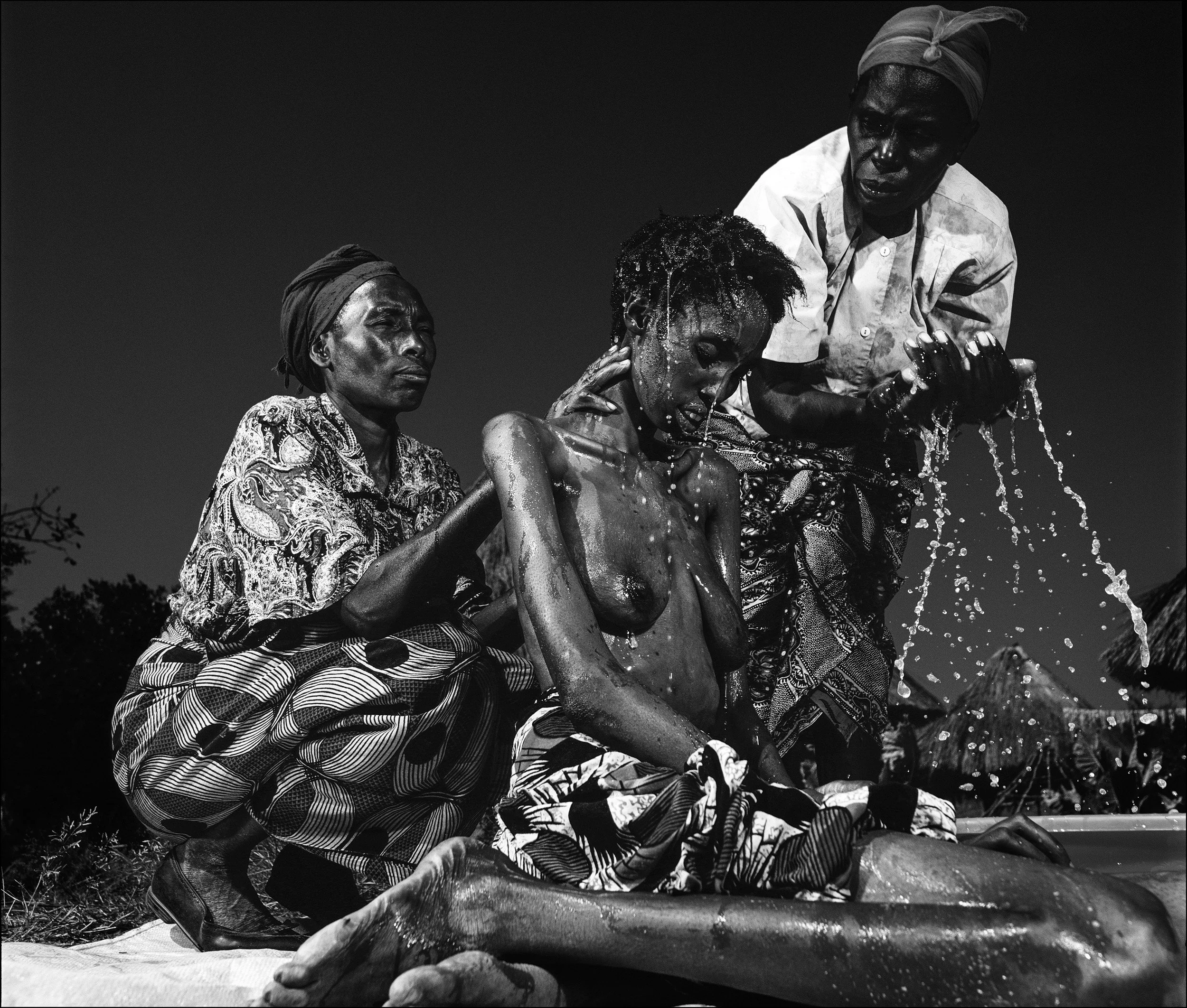 Zambia: A mother bathes her daughter who is dying from full-blown AIDS. Access to clean water is often difficult in remote parts of rural Africa and people living with HIV and other immuno-suppresant disease die more quickly as a result.
