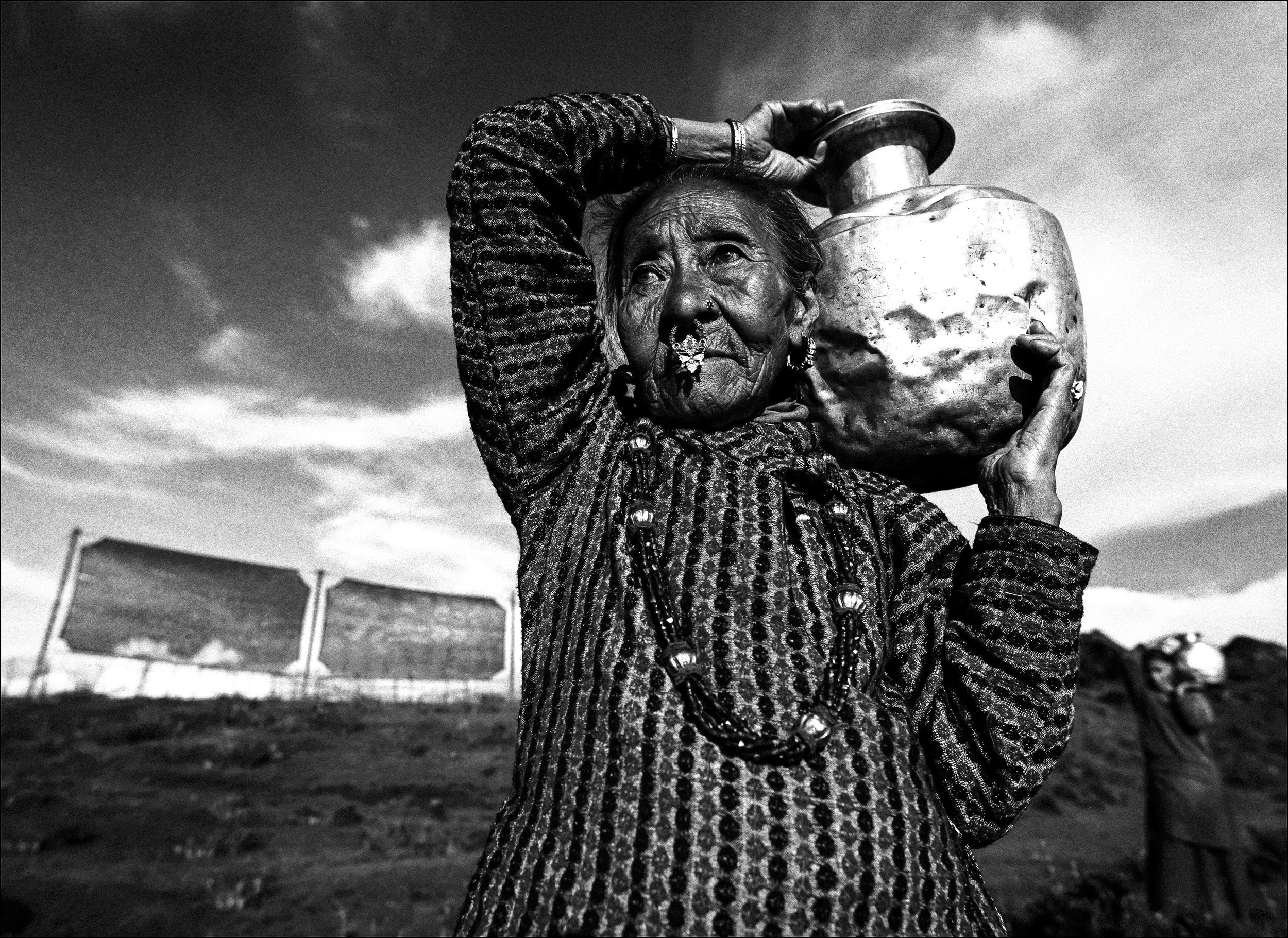 MEGMA, NEPAL: An old Nepali women fetches water from a reservoir created by harvesting the water vapour contained in fog high in the mountains of Nepal near the Indian border, Megma, Nepal. The fog passes through a netting system on the mountain top