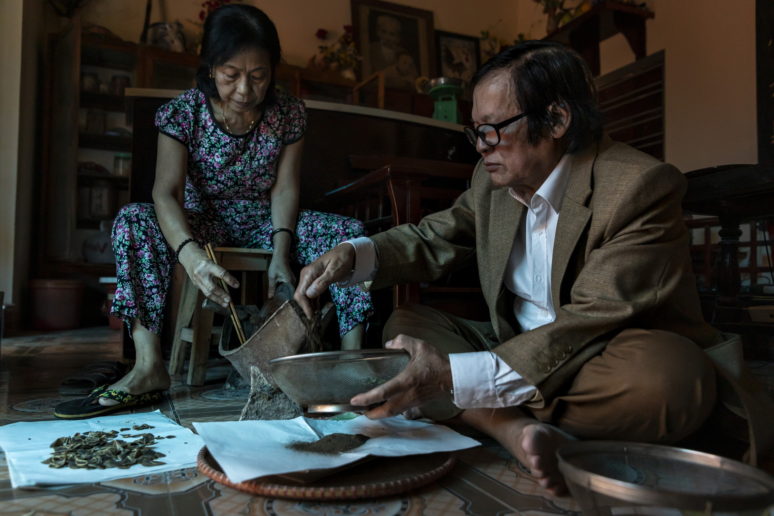 DUONGLAM, VIETNAM, 6 NOVEMBER 2018: Do Doan Quat, 71, a 6th generation traditional medicine doctor, is seen with his wife Tran Thi Thanh in their home. They grind pangolin scales and mix them with other herbs to create a medicine he believes is good