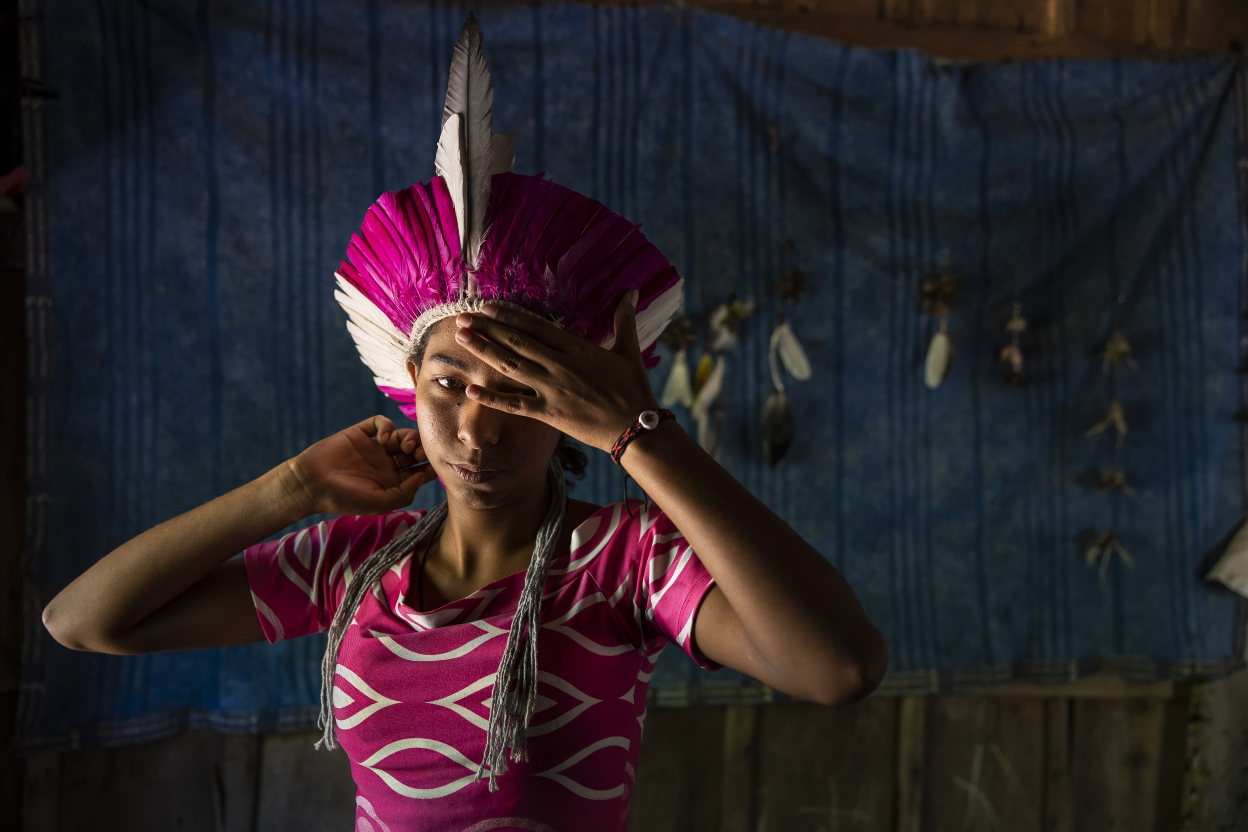 Baia Dos Guatos, Pantanal, Brazil: A girl from a Guatos indigenous indian family tries on a traditional head-dress she has just finished making. Ironically, this young girl and her sisters rediscovered their cultural heritage through Google and by