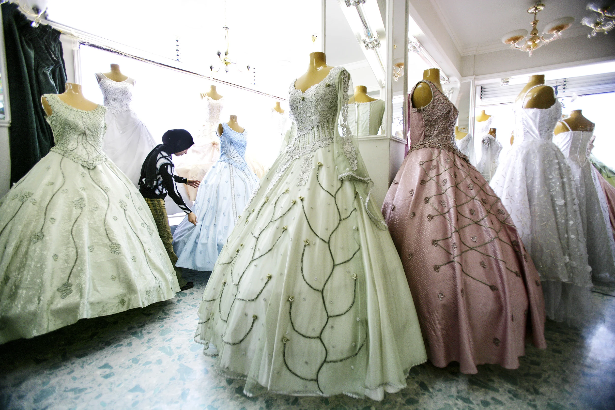 BAGHDAD, IRAQ - 24 FEBRUARY 2005. A young Iraqi woman wearing a Hijab headcovering looks through a range of modern evening dresses in a chic women's store in the Mansour neighbourhood of Baghdad. This western style of dress is threatened by the rise