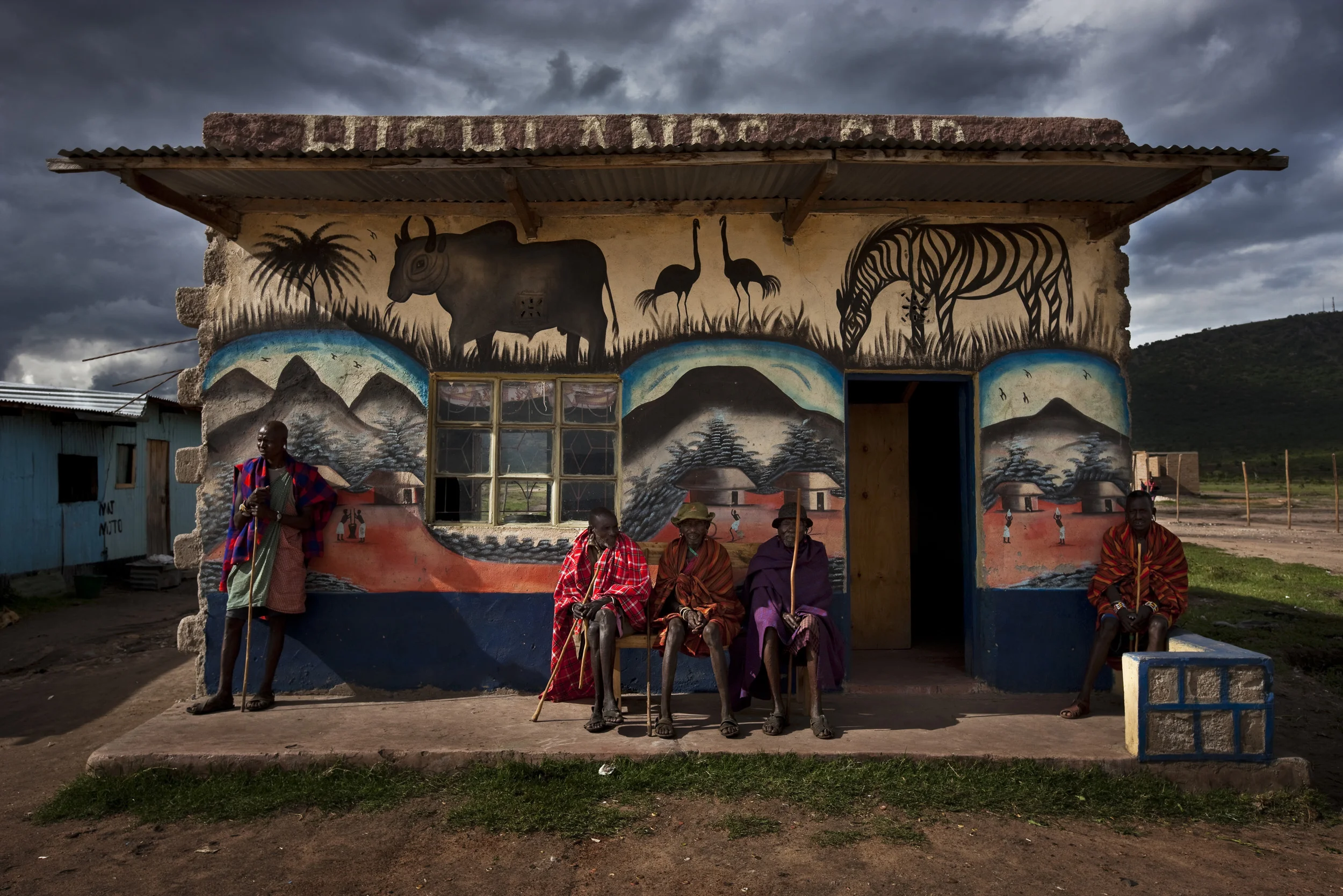 ORNGAYANET, NAROK SOUTH, KENYA, FEBRUARY 2010: Masaai elders sit outside a bar in a town which has grown up outside one of the gates of the Masaai Mara National Reserve, Orngayanet, 22 February, 2010, Kenya. This is a recent occurence, the elders w