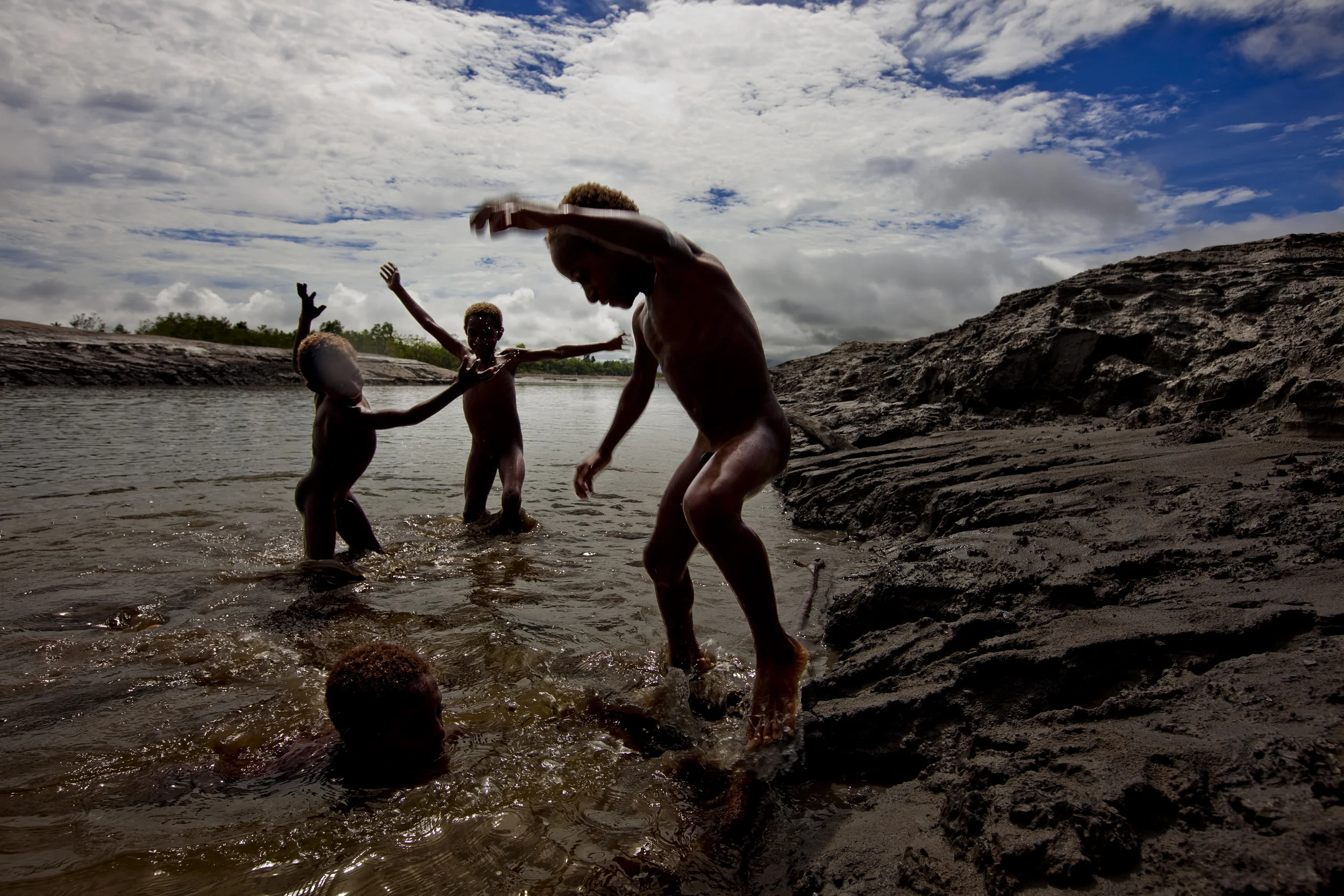 KIUNGA, WESTERN PROVINCE, PAPUA NEW GUINEA-JANUARY 2009: Images of local village children playing in the Ok Tedi river surrounded by banks of poisonous mine sediment which has been dumped into the Ok Tedi river by the mining process of Ok Tedi mine,