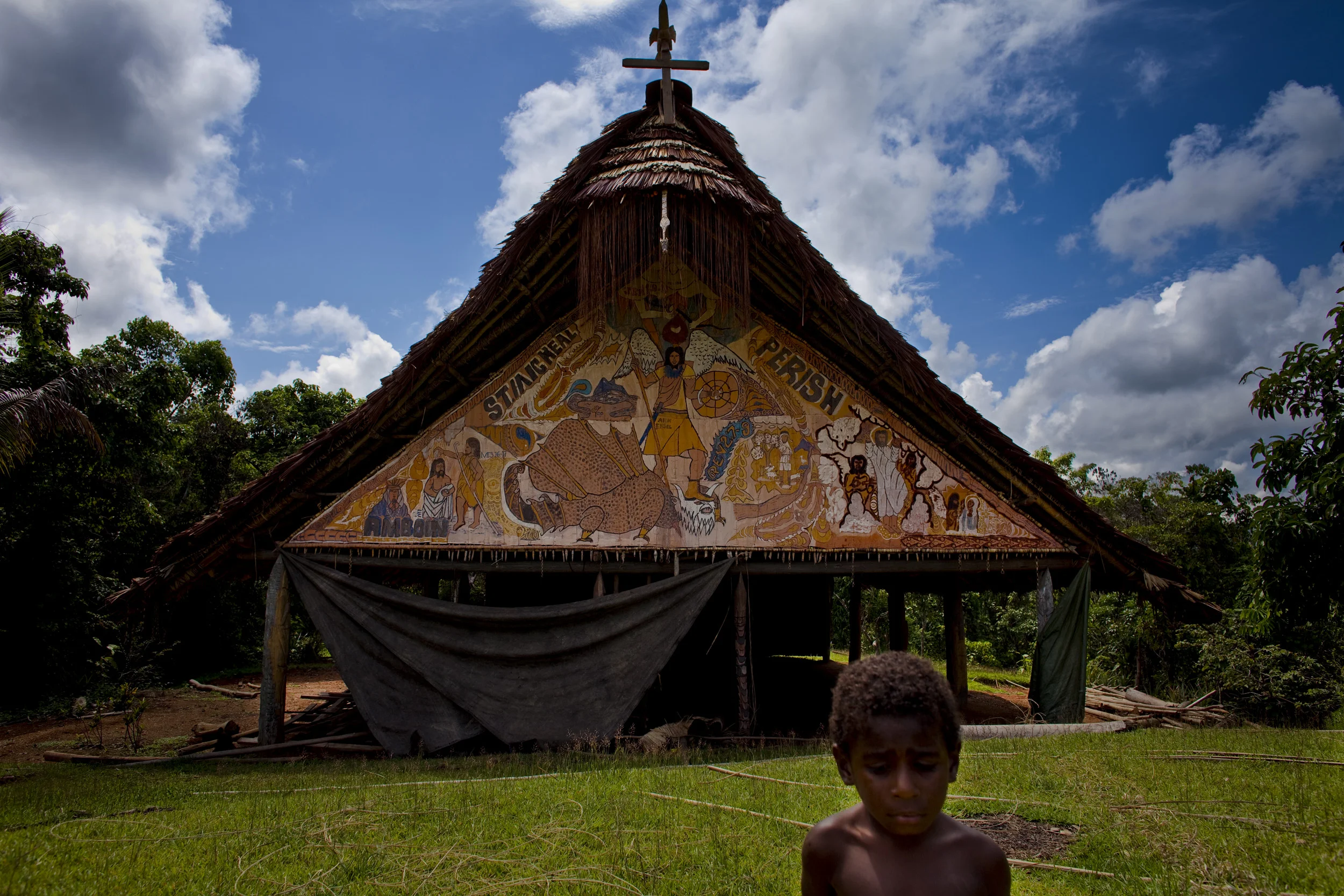 MIDDLE SEPIK, PAPUA NEW GUINEA-DECEMBER 2008: An image of a young boy standing by a newly erected Catholic church in a building which used to be the Spirit house of the Karawari people of this village in the middle Sepik river, 15 December 2008. The