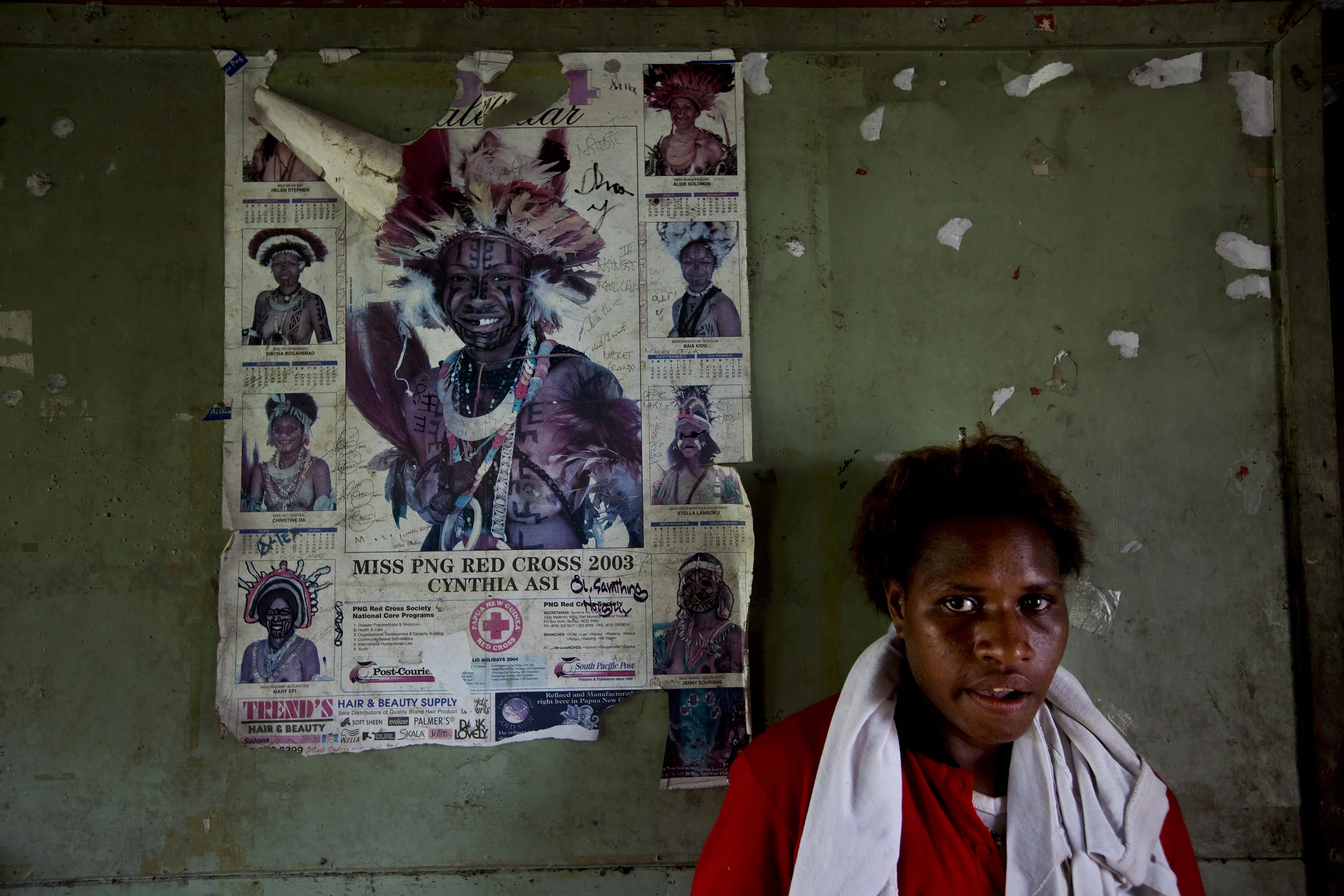 LAKE MURRAY, WESTERN PROVINCE, PAPUA NEW GUINEA-JANUARY 2008: A teenage girl in western clothes stands in her house next to an old poster advertising a Miss PNG contest sponsored by an NGO. All sense of personal identity has changed very quickly in