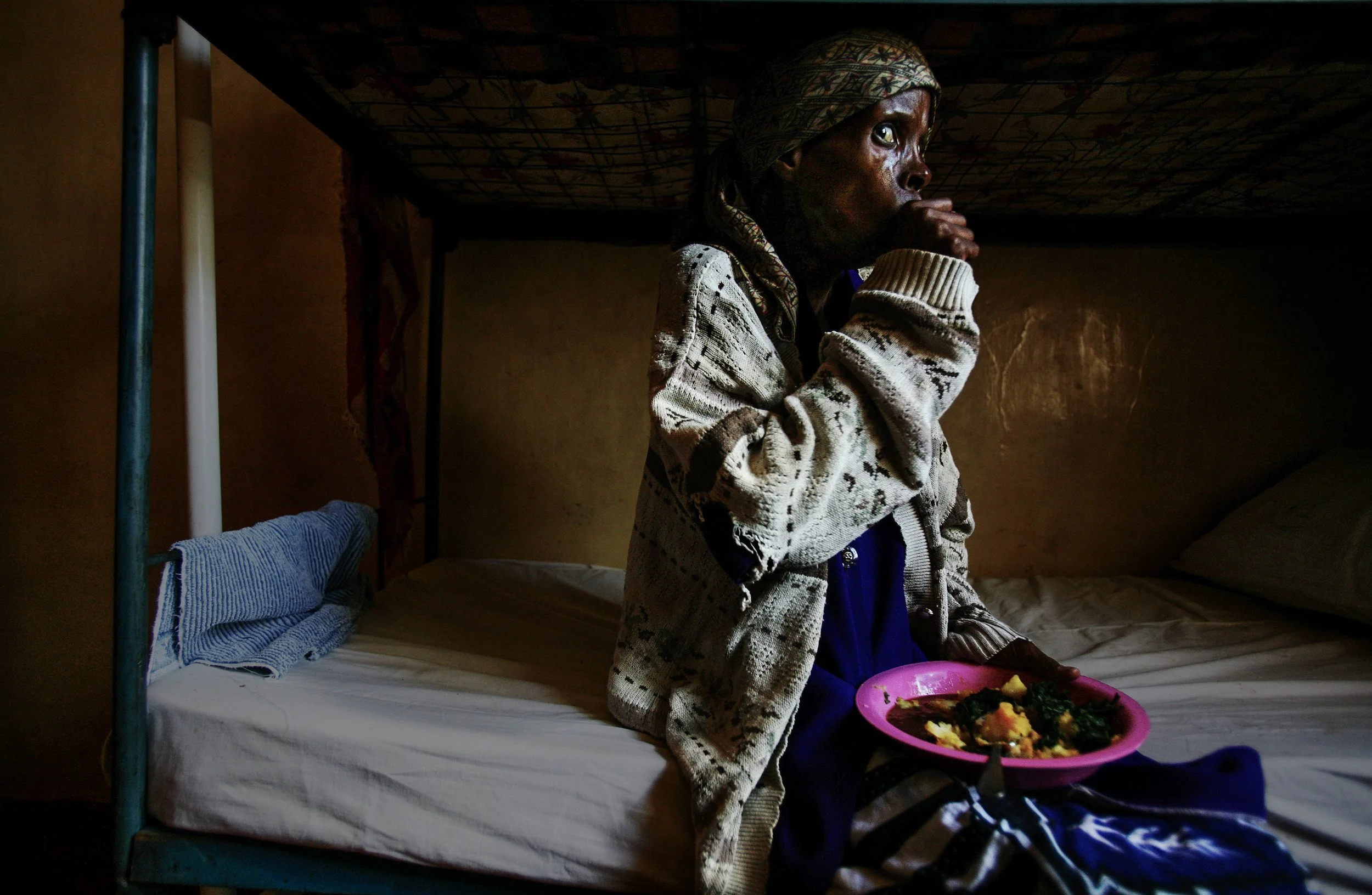 Meru, Kenya-28 November 2006: Elisabeth Mweru,28, coughs while feeding herself again for the first time in weeks as she recovers from severe tuberculosis. Elizabeth was found in an advanced stage of full blown Aids by a group of self-supporting HIV+