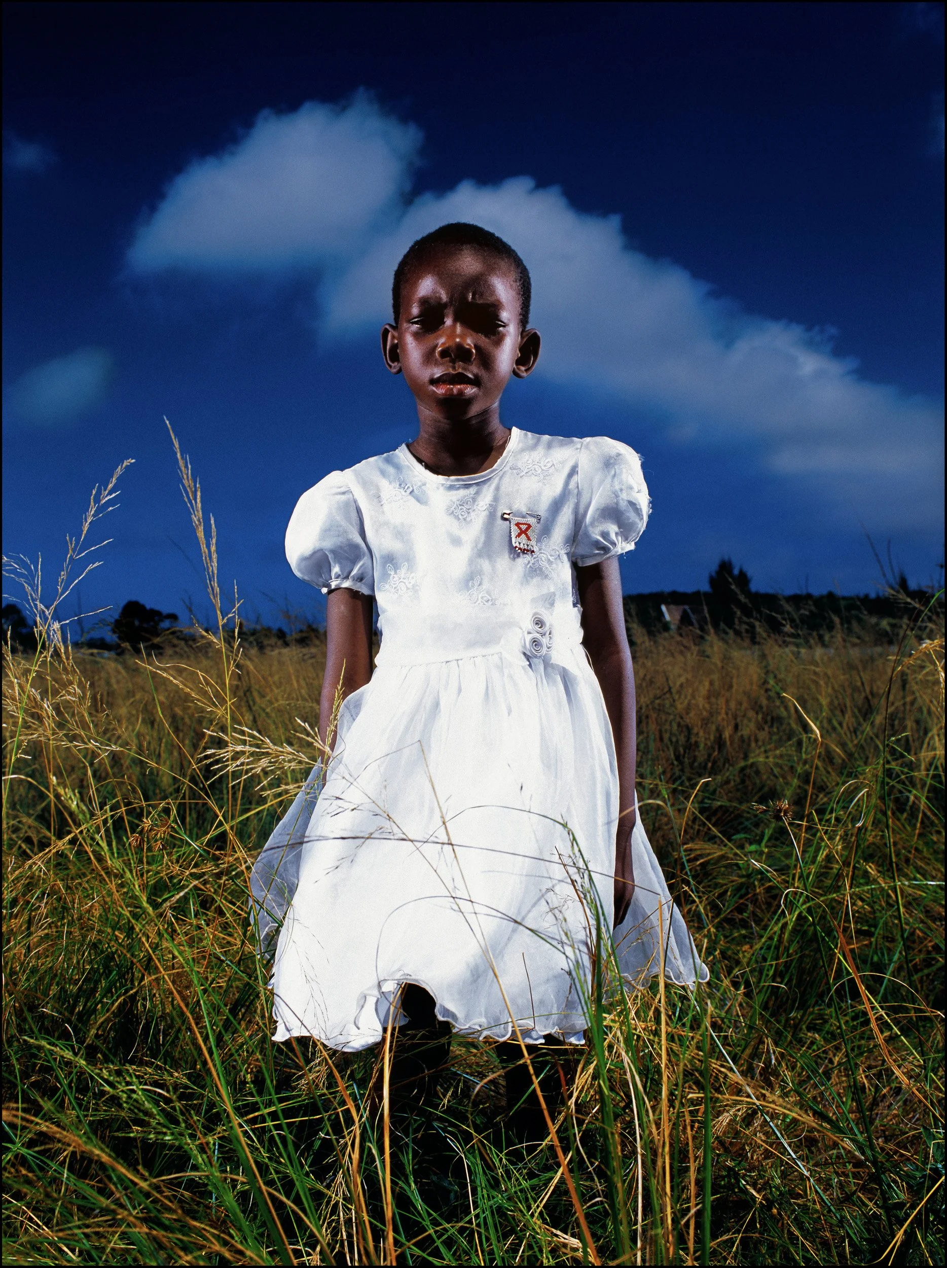 RICHARDS BAY, SOUTH AFRICA-MAY 2004: A young aids orphan stands alone in a field after a church service.