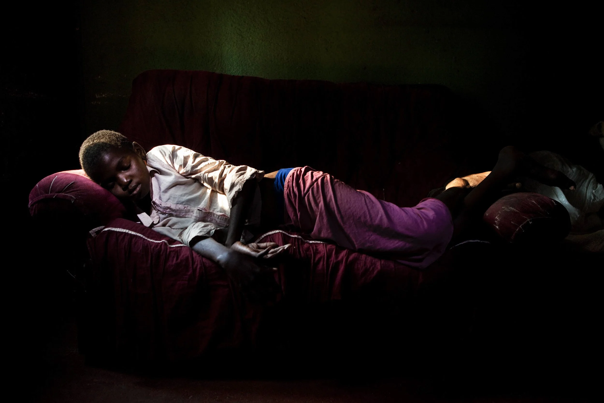 HARARE, ZIMBABWE, JUNE 2009: A severely ill HIV+ 16 year old girl is tended by her sister in a one bedroom shack in a makeshift township in Harare, Zimbabwe, 21 June 2009. They live with their grandmother as their parents died of Aids 5 years previou