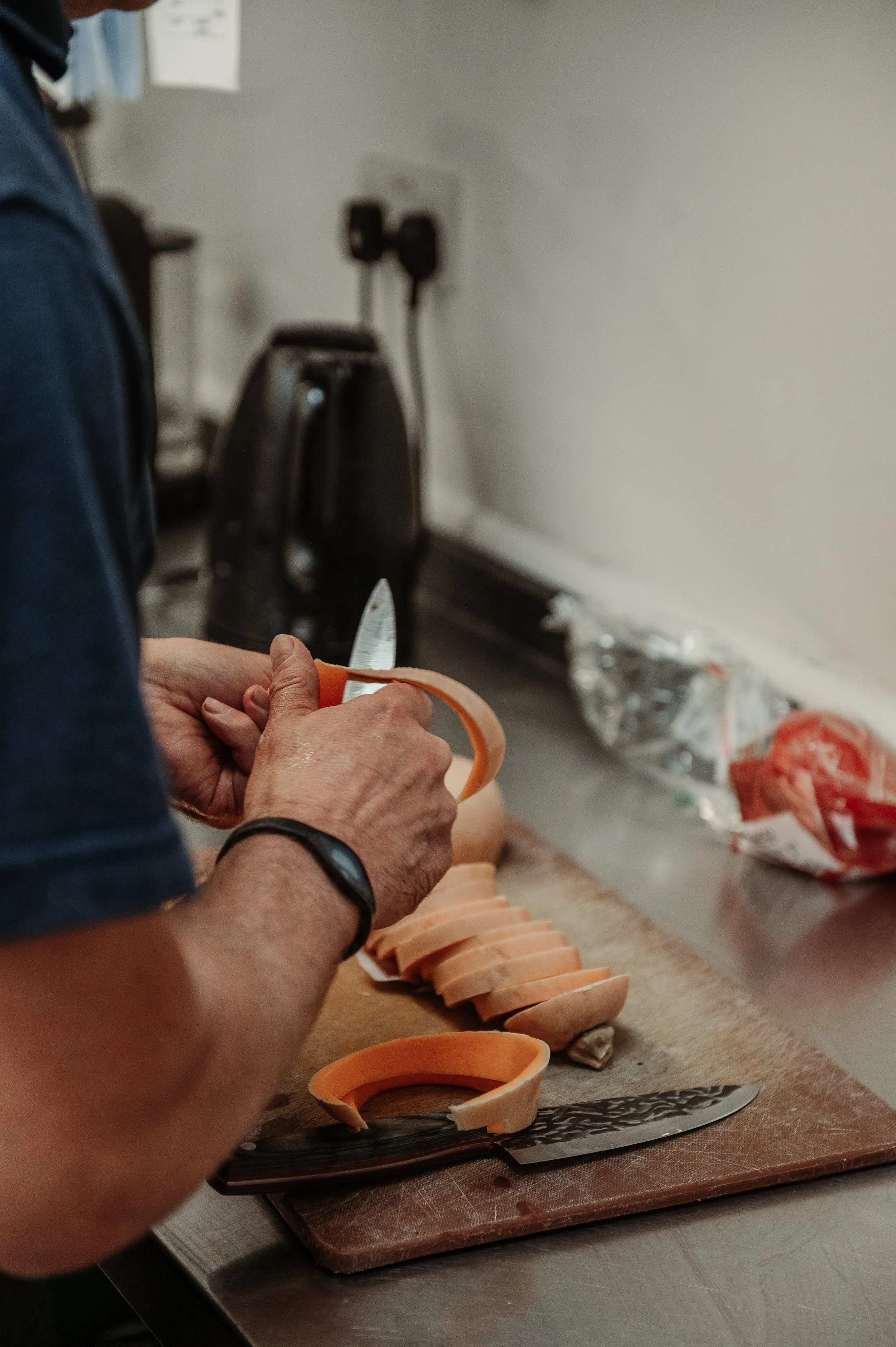 Person slicing sweet potato on a cutting board in a kitchen.