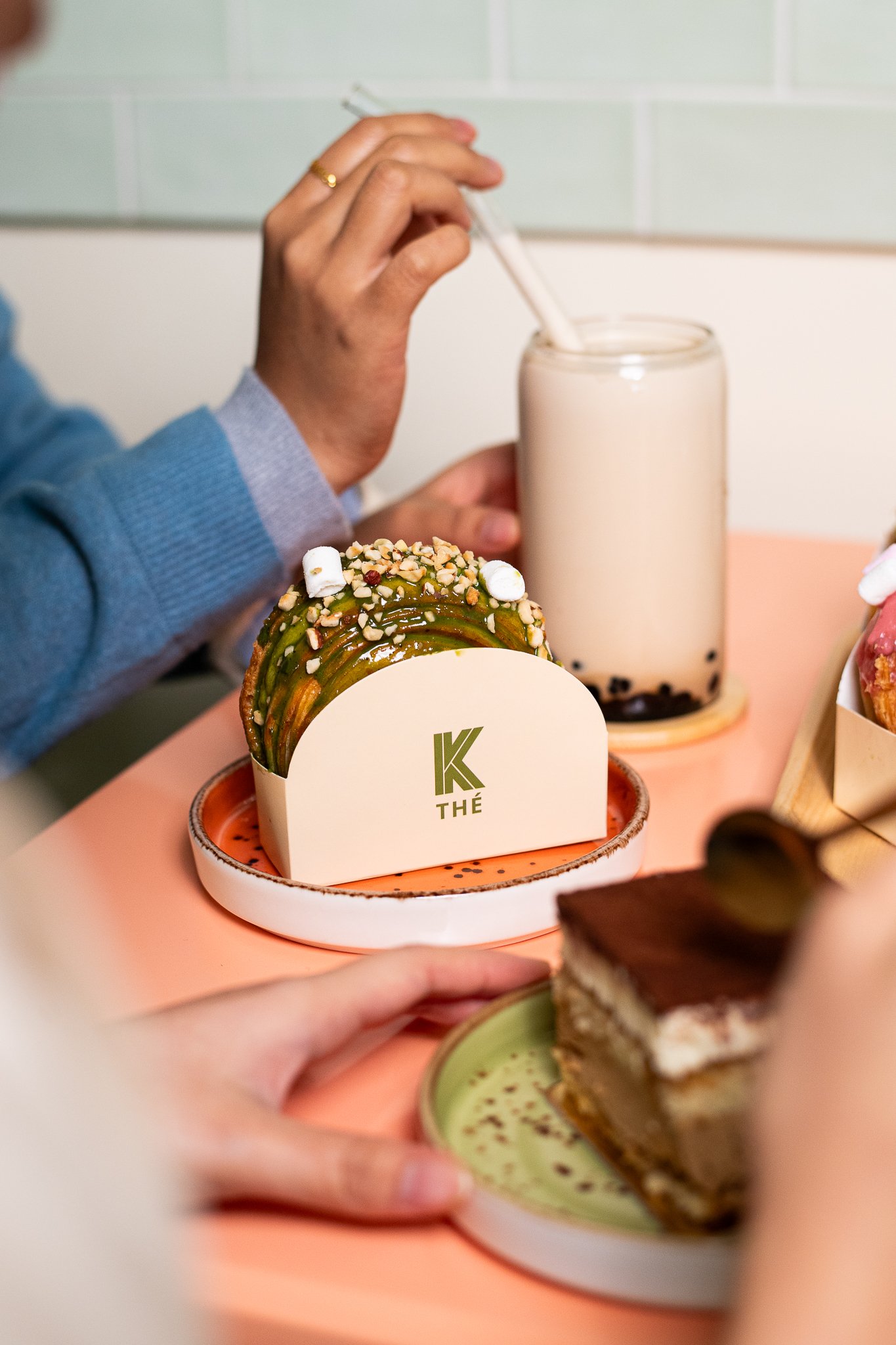 Gâteau et boissons dans un café, y compris un gâteau vert décoré de noix et une boisson avec perles de tapioca.