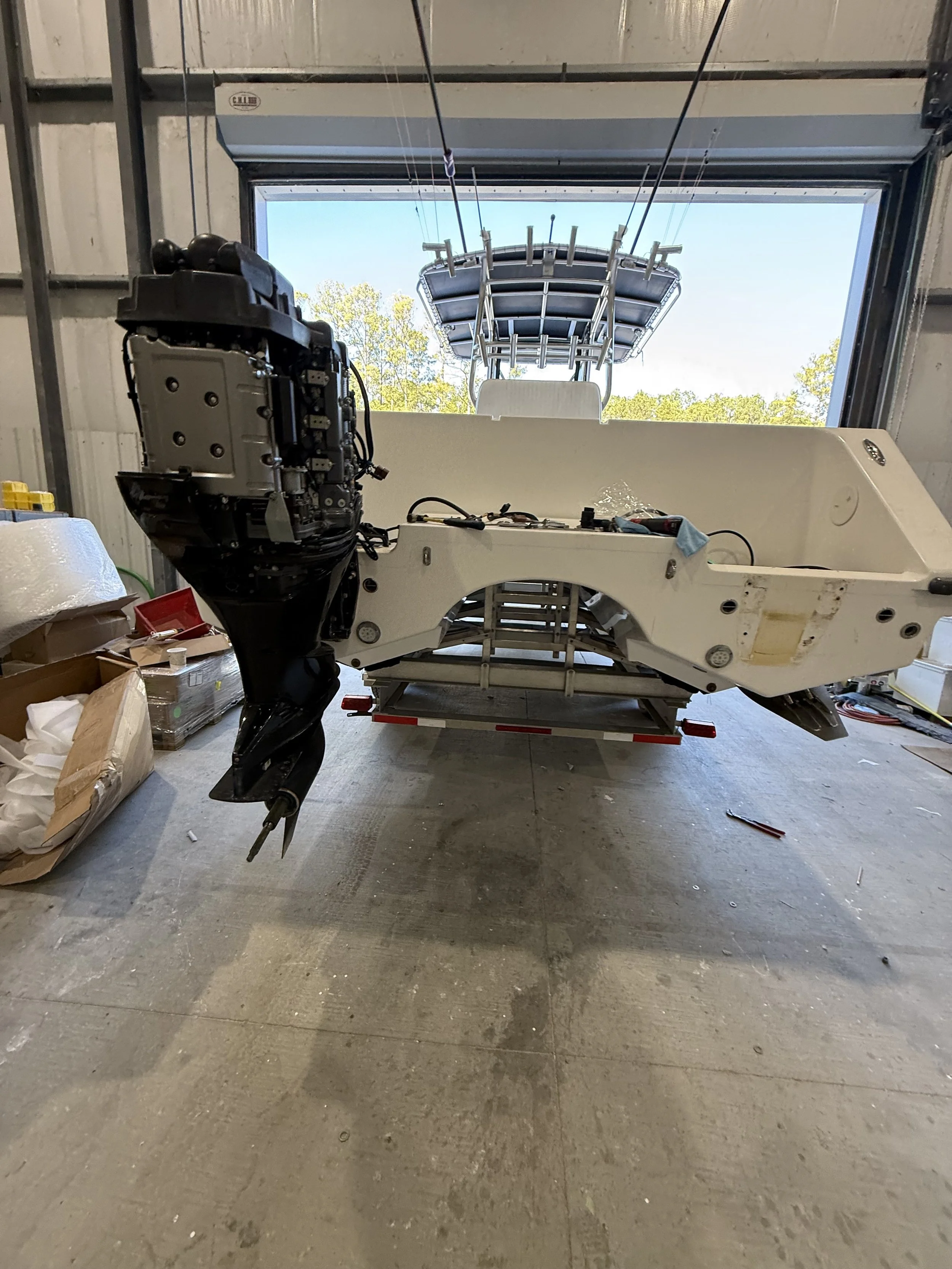 A boat with an engine removed is inside a garage, with part of the boat and engine visible through an open garage door.