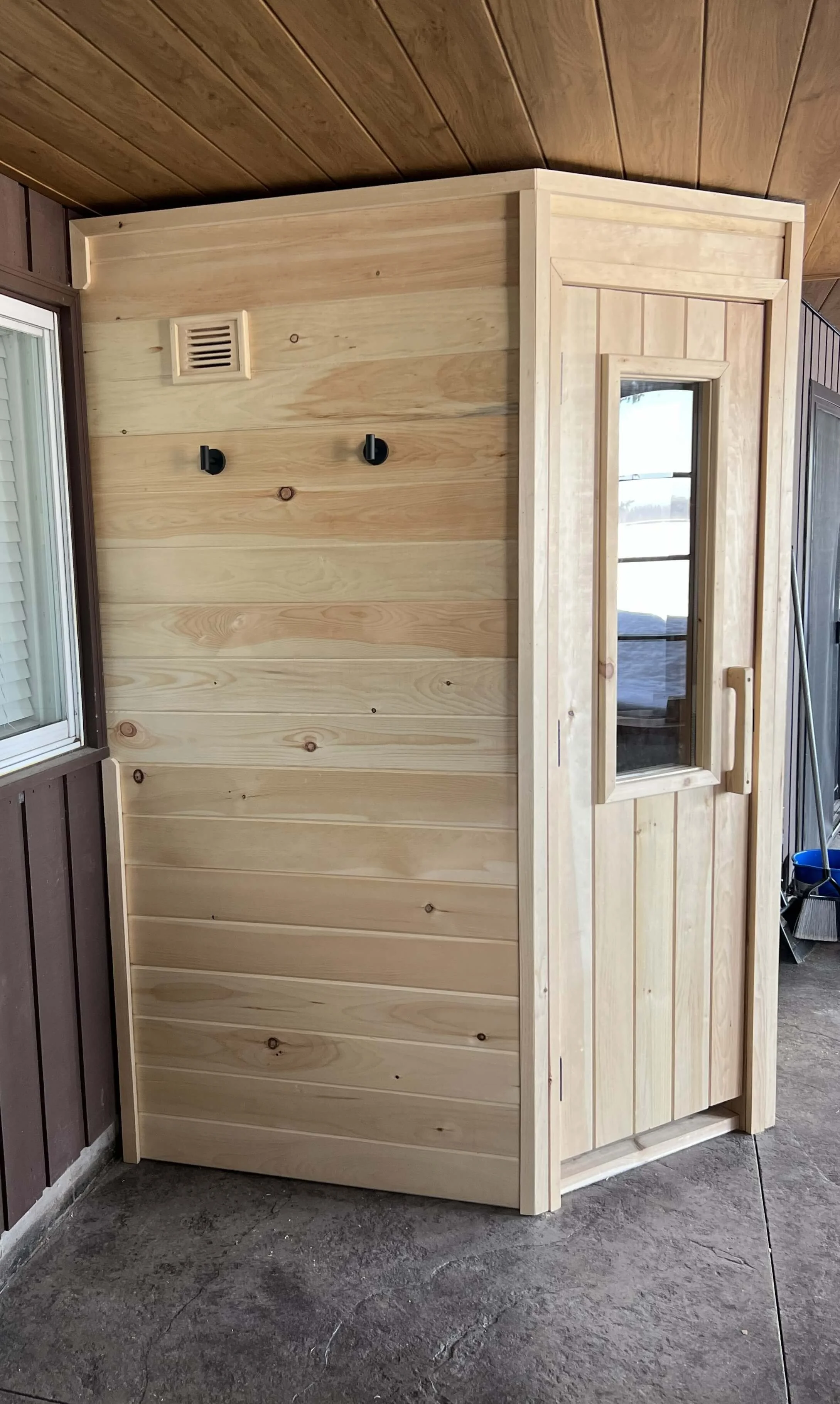 Side view of custom backyard sauna with pine siding and compact 174 cubic foot design, built for efficient heating in Canadian winters.