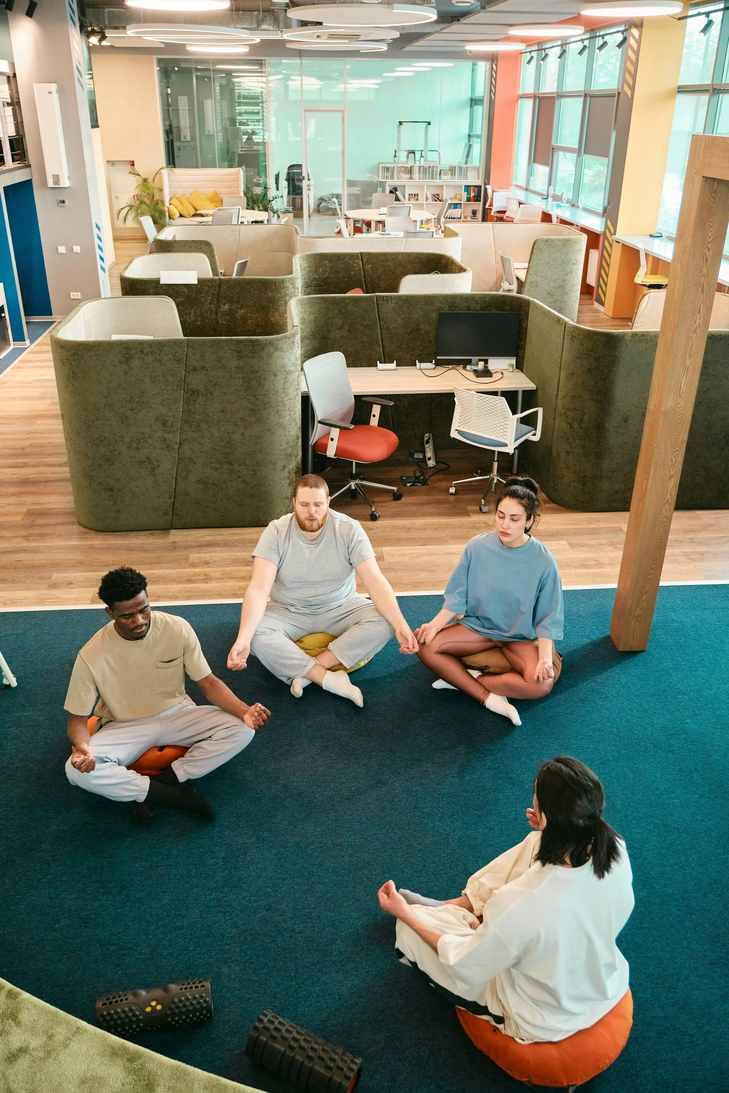 Four people sitting on a blue carpet in a circle, in a meditation workshop .