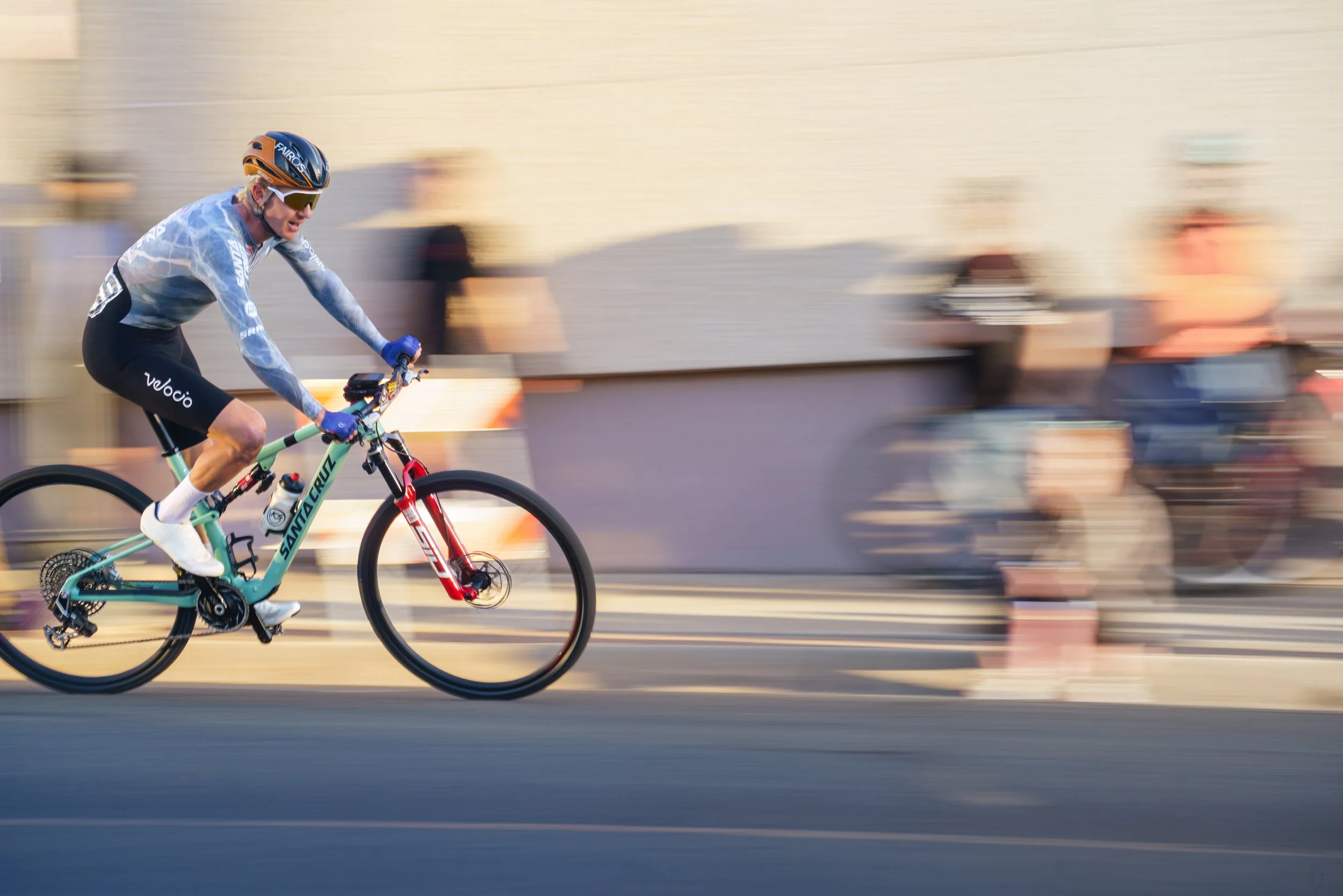 A person riding a bicycle at high speed with motion blur on a city street during daytime.