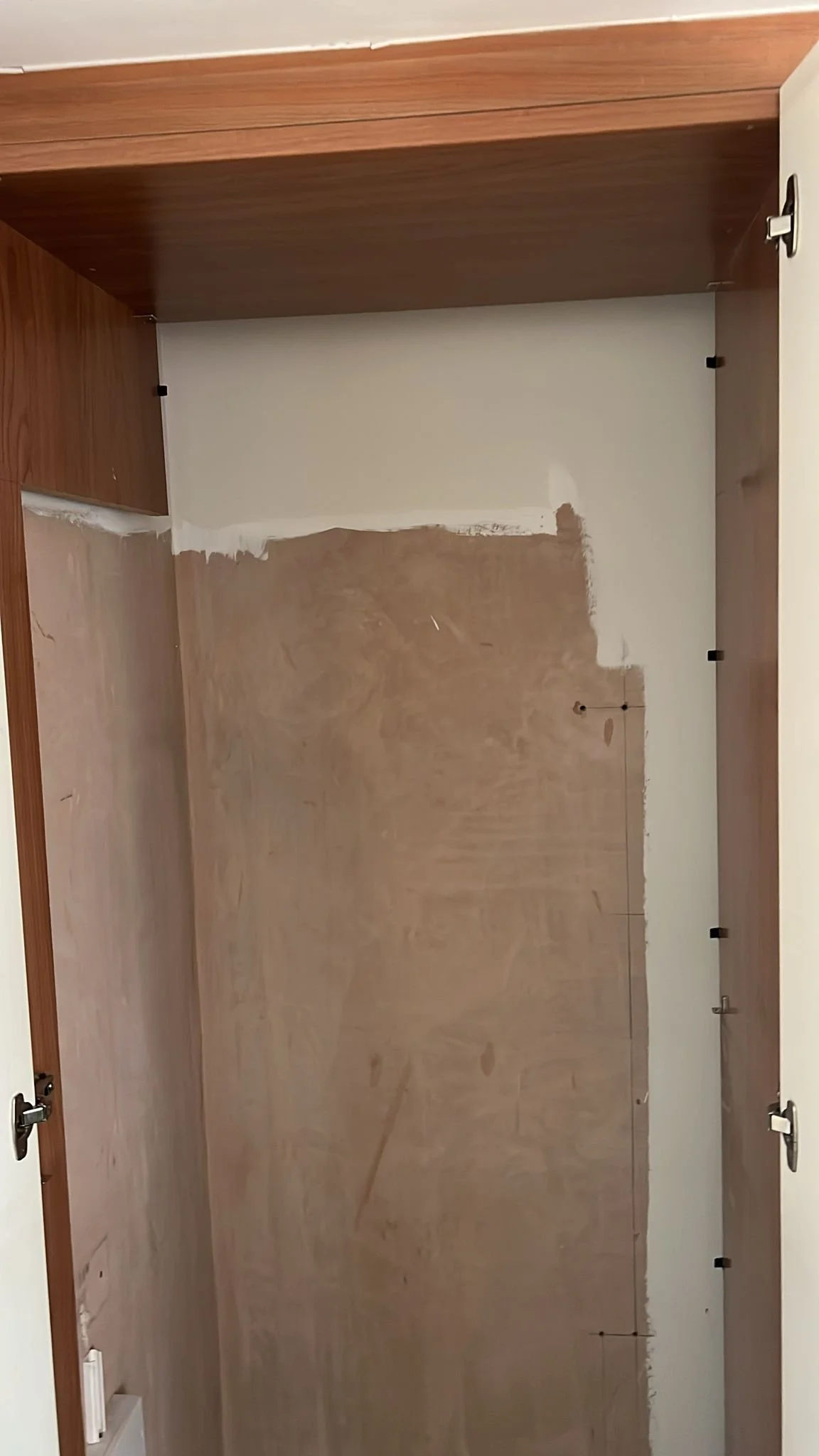 An empty room with wooden flooring and white walls, inside a house or apartment under renovation or remodeling.