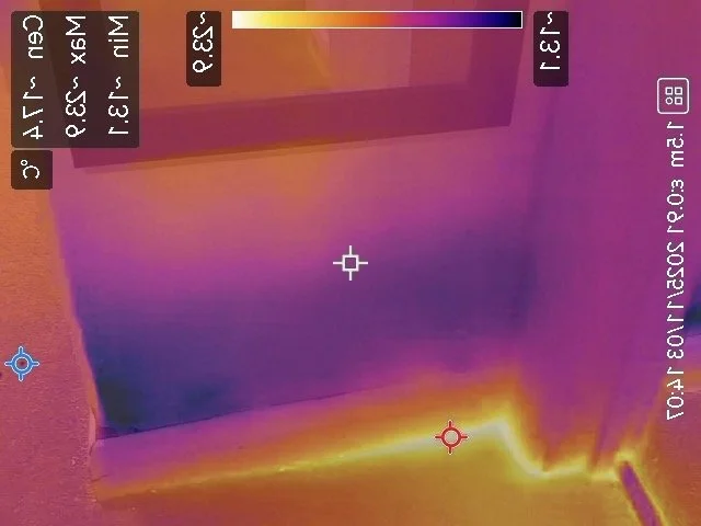 Thermal image of a room with a door and a student desk, showing heat signatures with warm areas in yellow and orange and cooler areas in purple and blue.