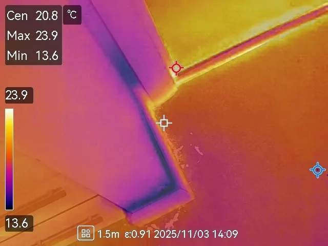 Thermal image of a corner where two walls meet, showing temperature variations from 13.6°C to 23.9°C, with warmer areas in yellow/orange and cooler areas in purple.
