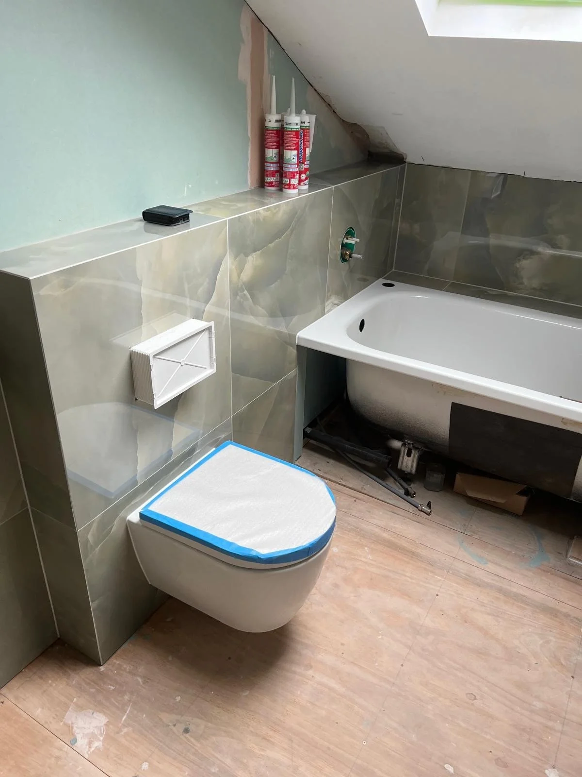 Bathroom with a toilet, bathtub, and construction materials, indicating ongoing renovation.